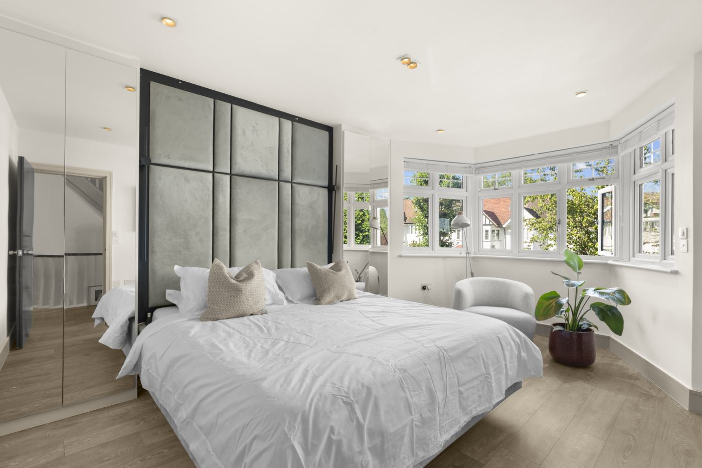 Main bedroom with upholstered headboard and bay window, High Barnet short-let property