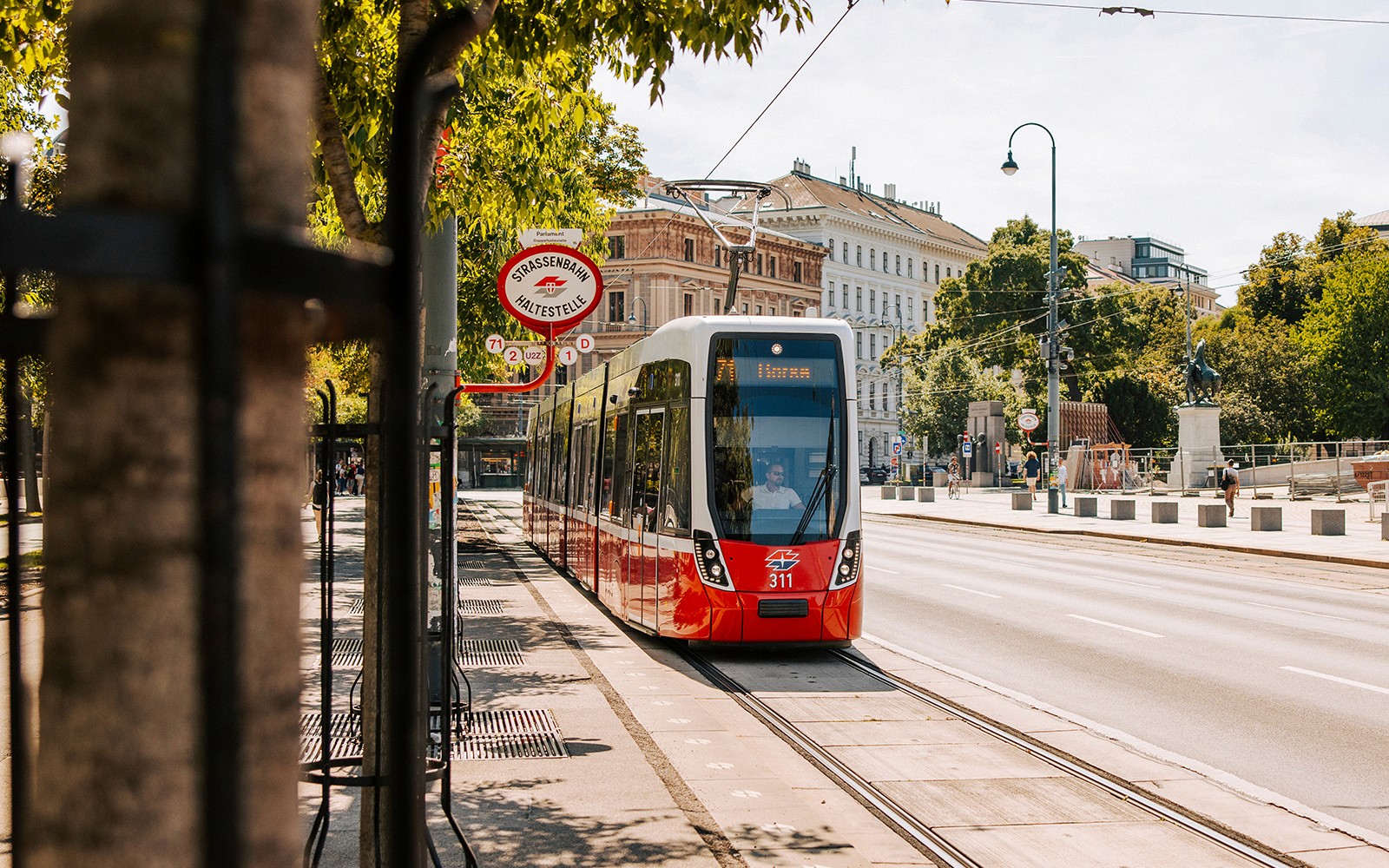 Tram on Vienna street near historic buildings, part of Vienna City Card benefits.
