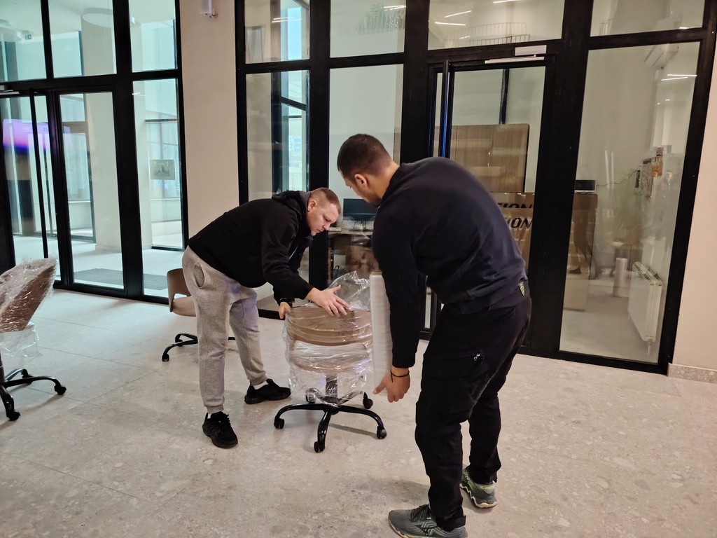 Radnici Ares Selidbe pažljivo pakuju i pomeraju kancelarijsku stolicu tokom poslovne selidbe.