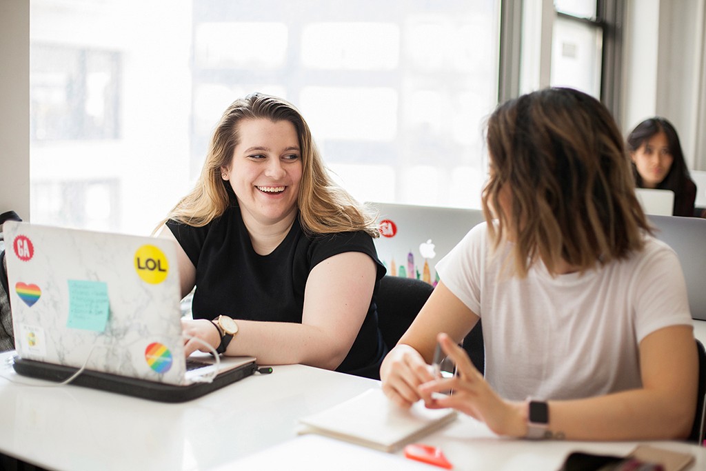 Hands in active collaboration over a shared surface, building and refining together.