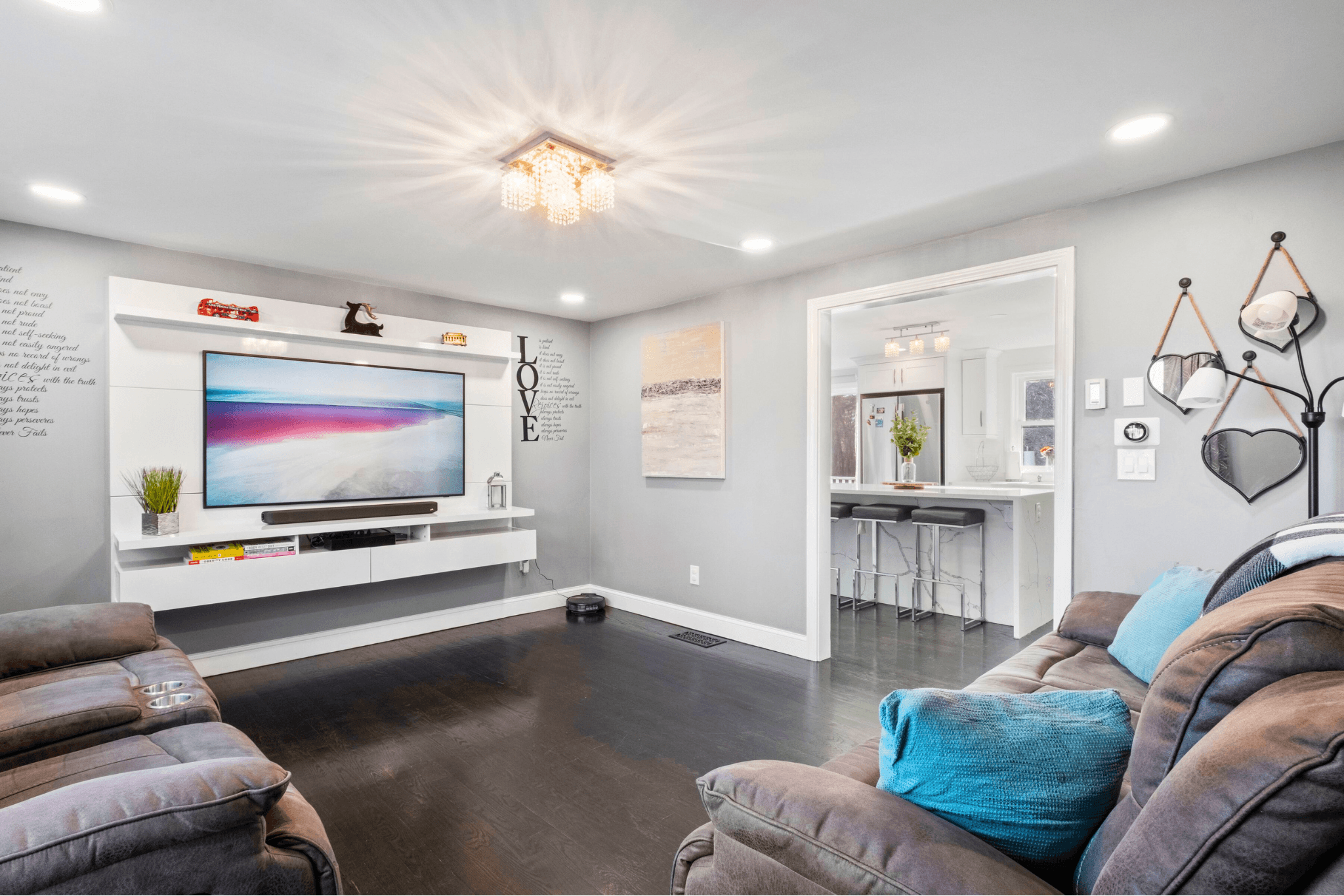 Open-concept living room with gray walls, sleek wood floors, modern lighting, and cozy seating, designed for guest comfort at this Massachusetts short-term rental.