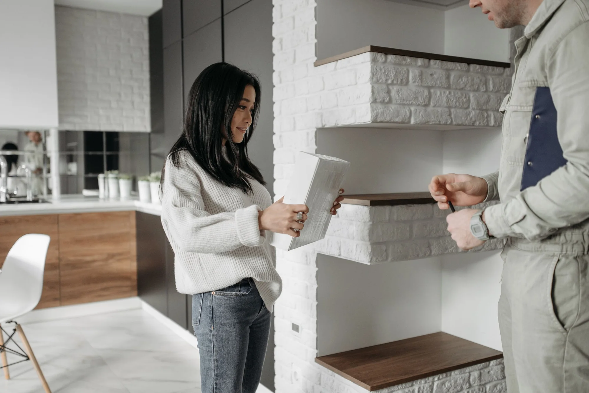 A tradesman talking with a homeowner in her kitchen