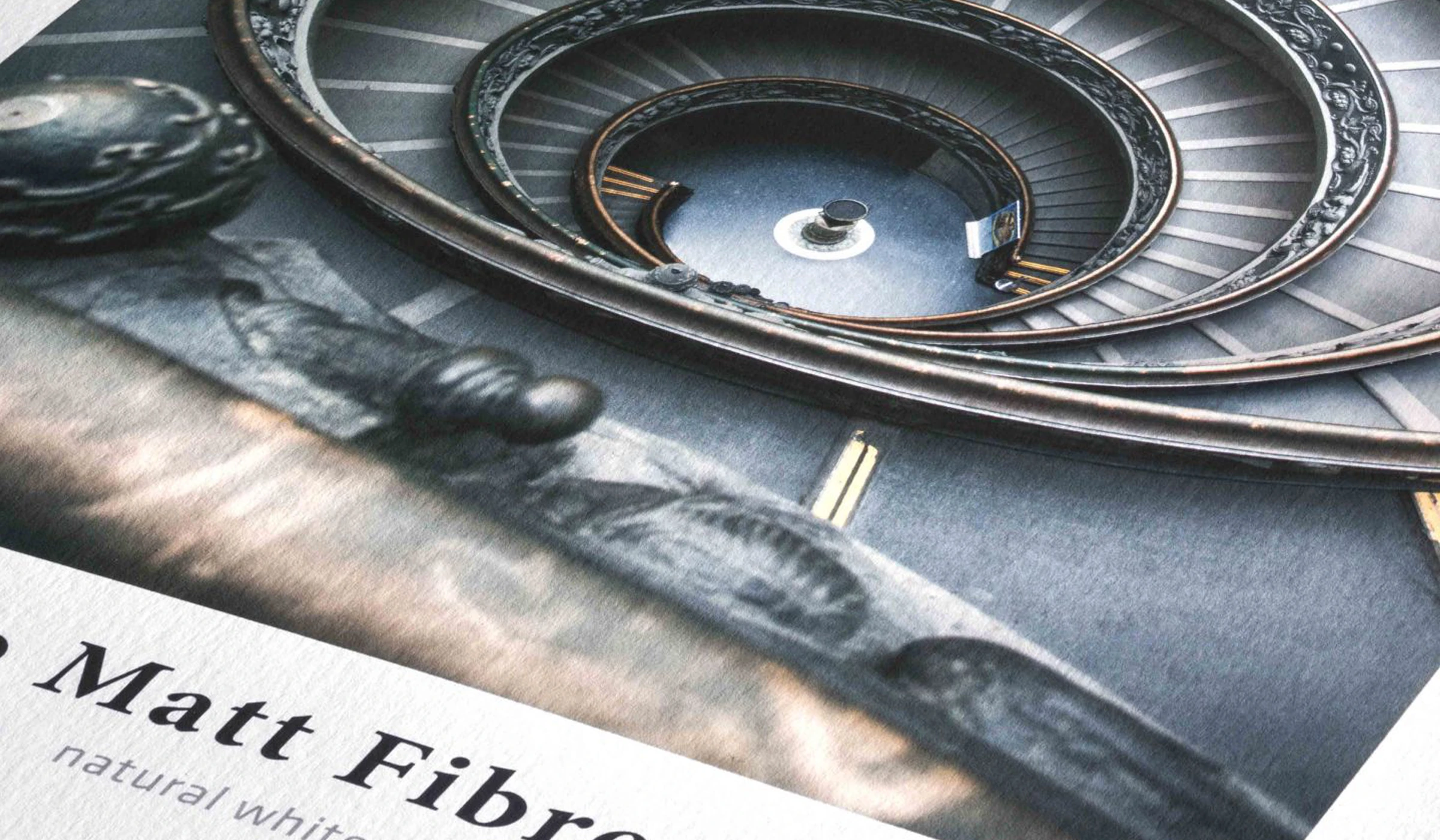 Zbliżenie na wydruk zdjęcia na papierze Hahnemühle Matt Fibre 200 z widoczną fakturą papieru i fragmentem spiralnych schodów