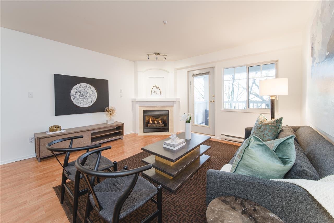 A cozy living room featuring a sofa, decorative pillows, a fireplace, and large windows with natural light.