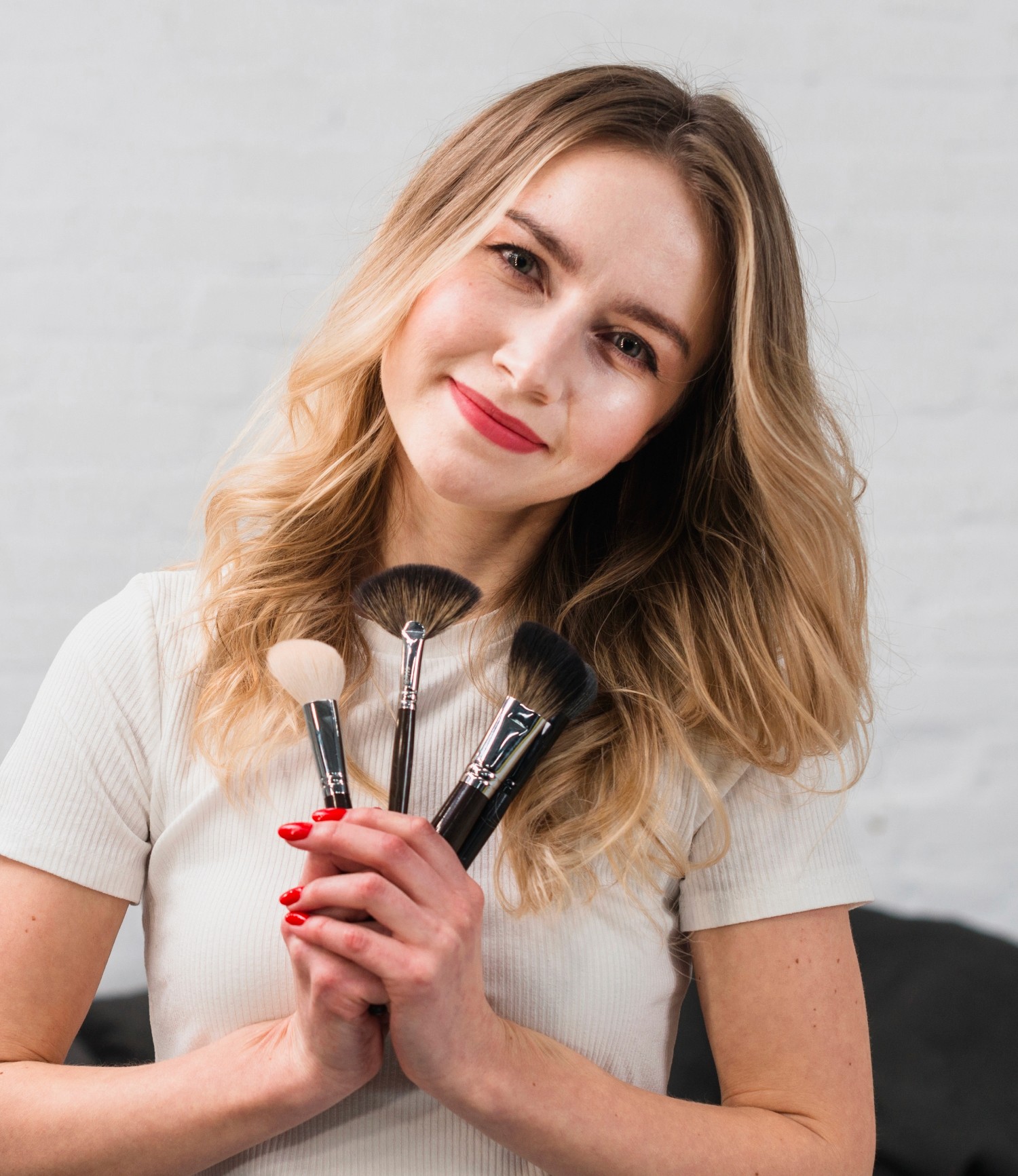 portrait photo of a makeup artist holding makeup brushes