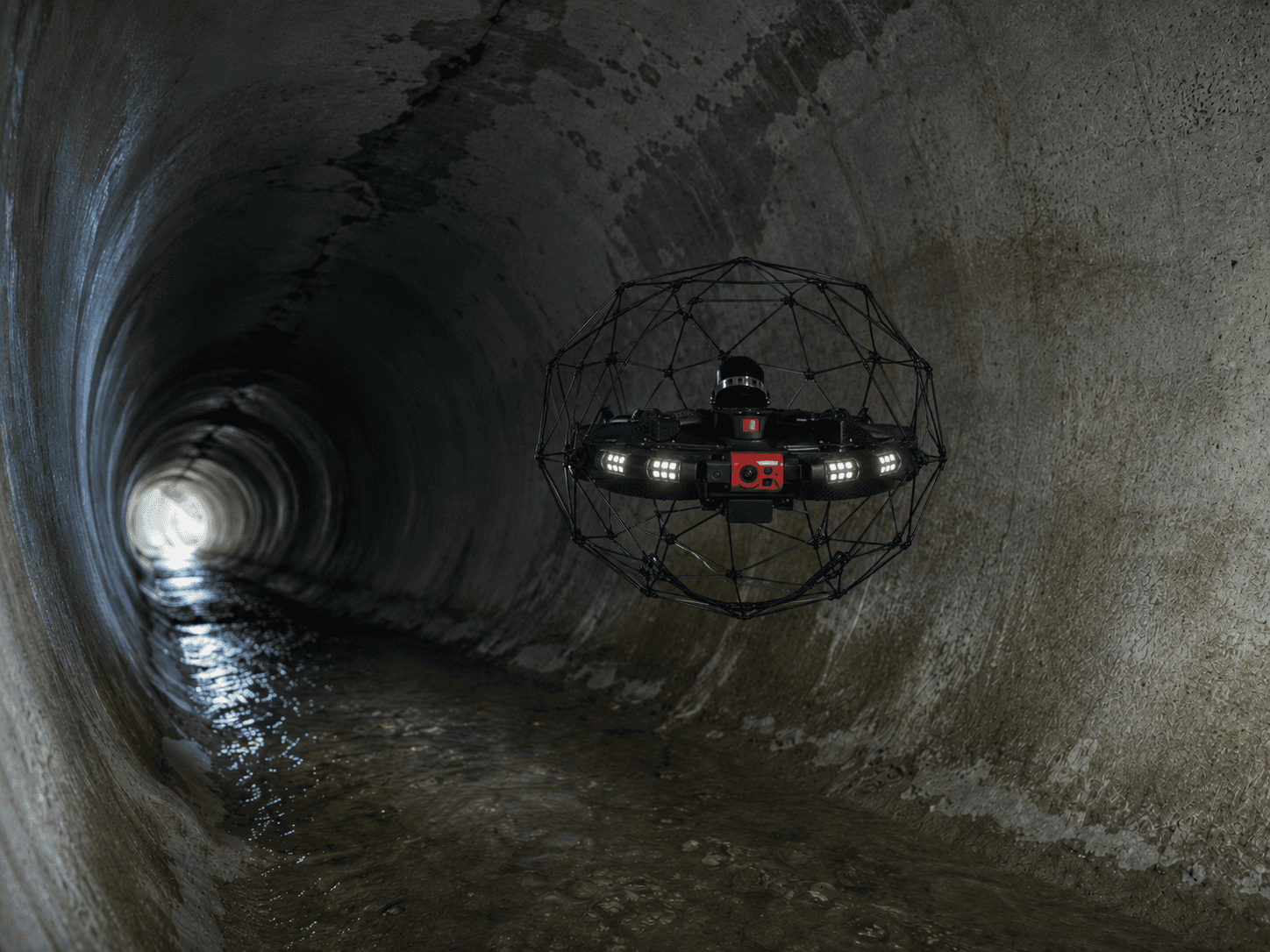 Collision-tolerant inspection drone flying inside a concrete culvert with lights on