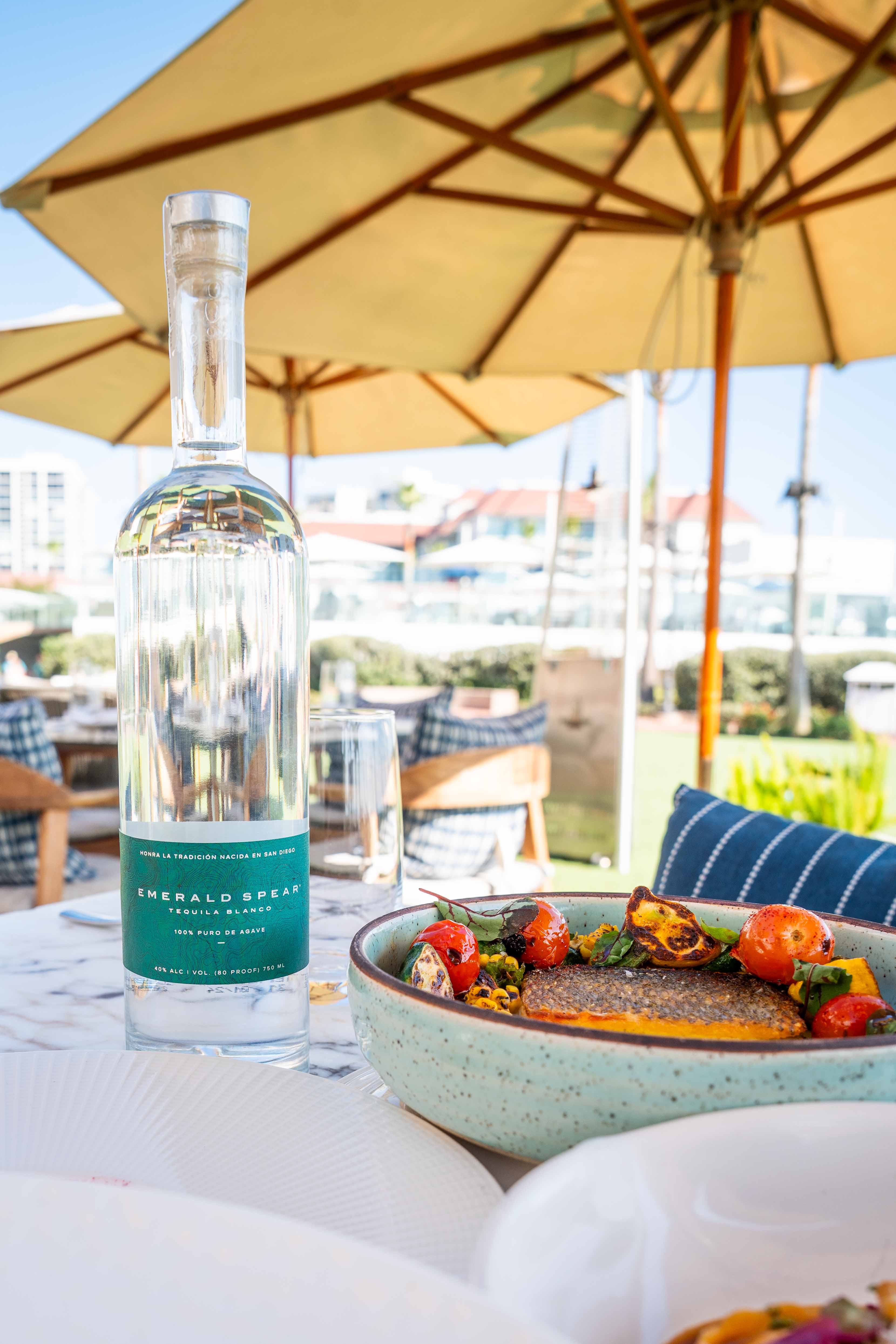Emerald Spear Tequila bottle under an umbrella paired with a dish of food from Serea Coastal