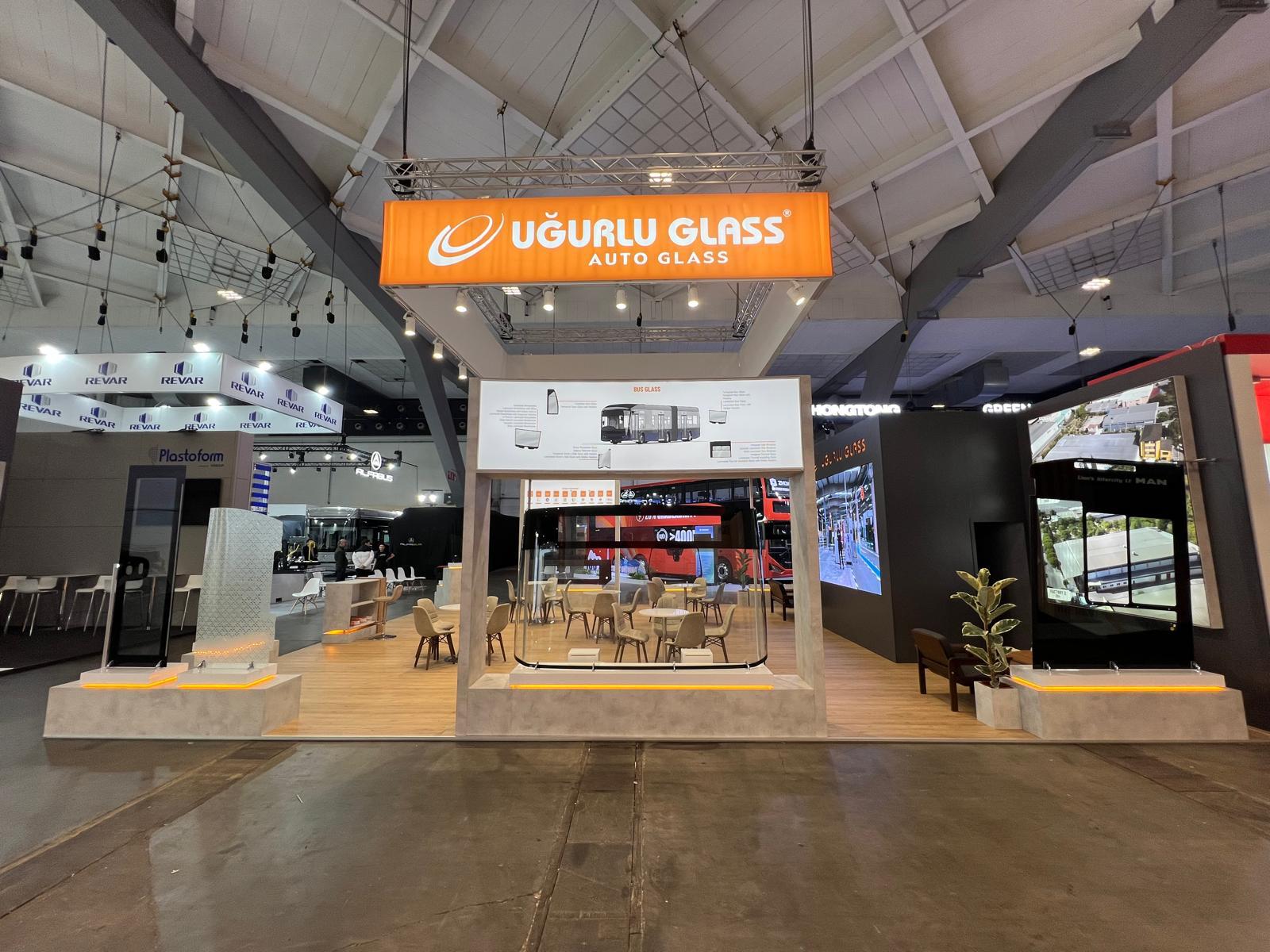Real automobile glass products displayed on dedicated illuminated bases at the Uğurlu Glass stand.