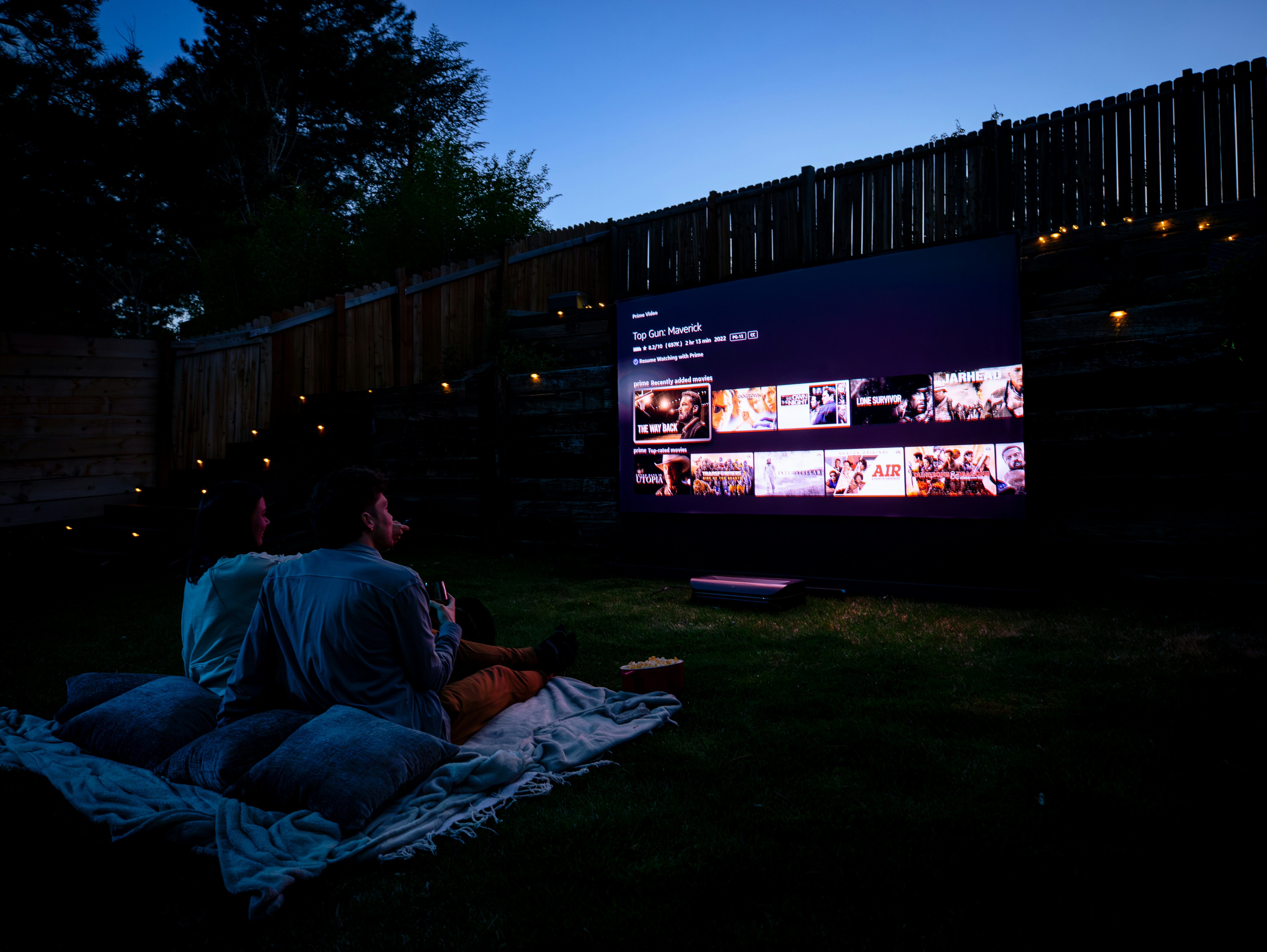 Two people sitting on a blanket watching a movie