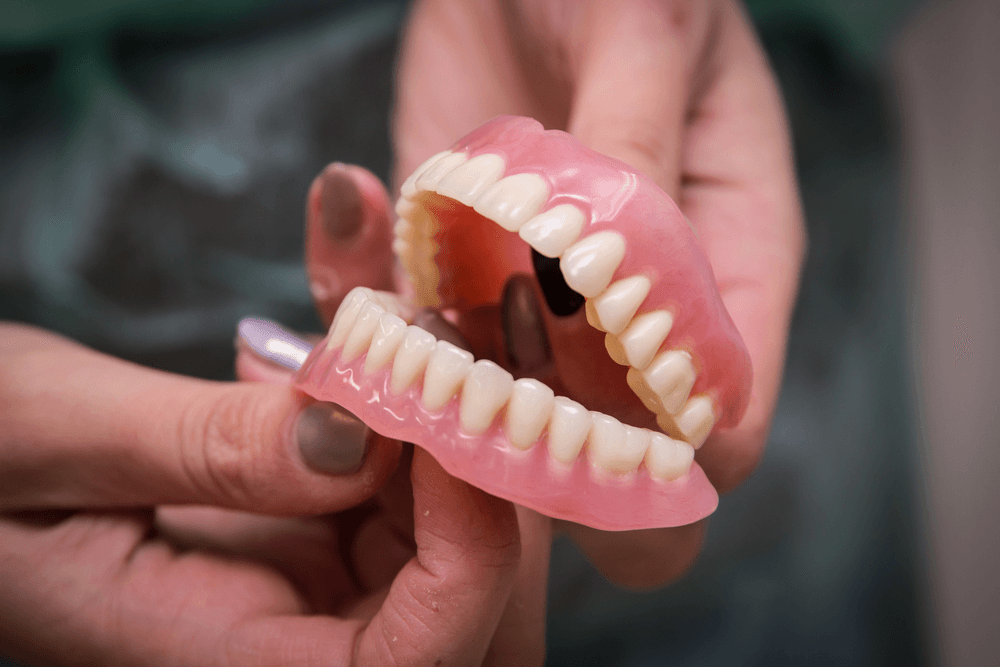 Hands holding a full set of removable dentures