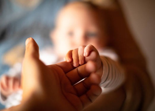 baby holding mother's hand