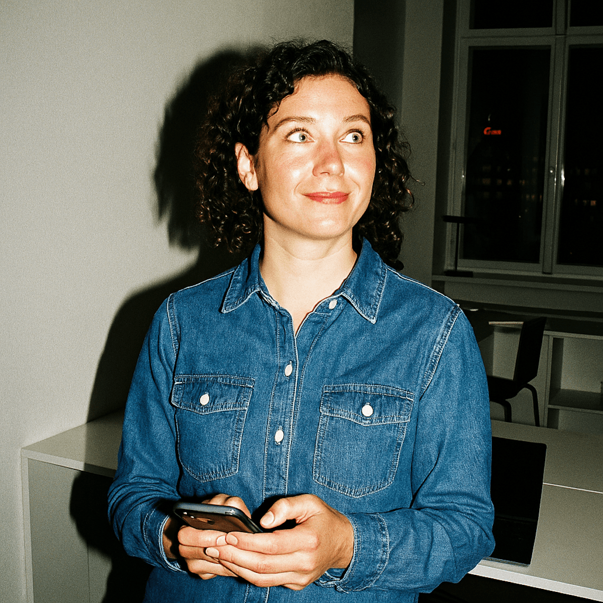 Curly haired woman holding smartphone.