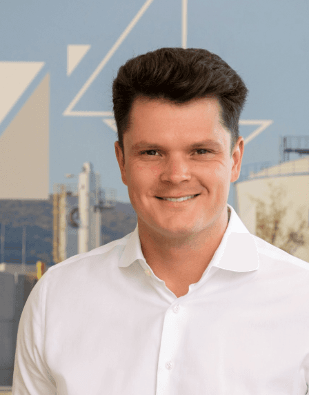 Nils Boden, Energieberater bei wattkonzept, mit weißem Poloshirt vor modernem Gebäude mit grünen Fassadenelementen.