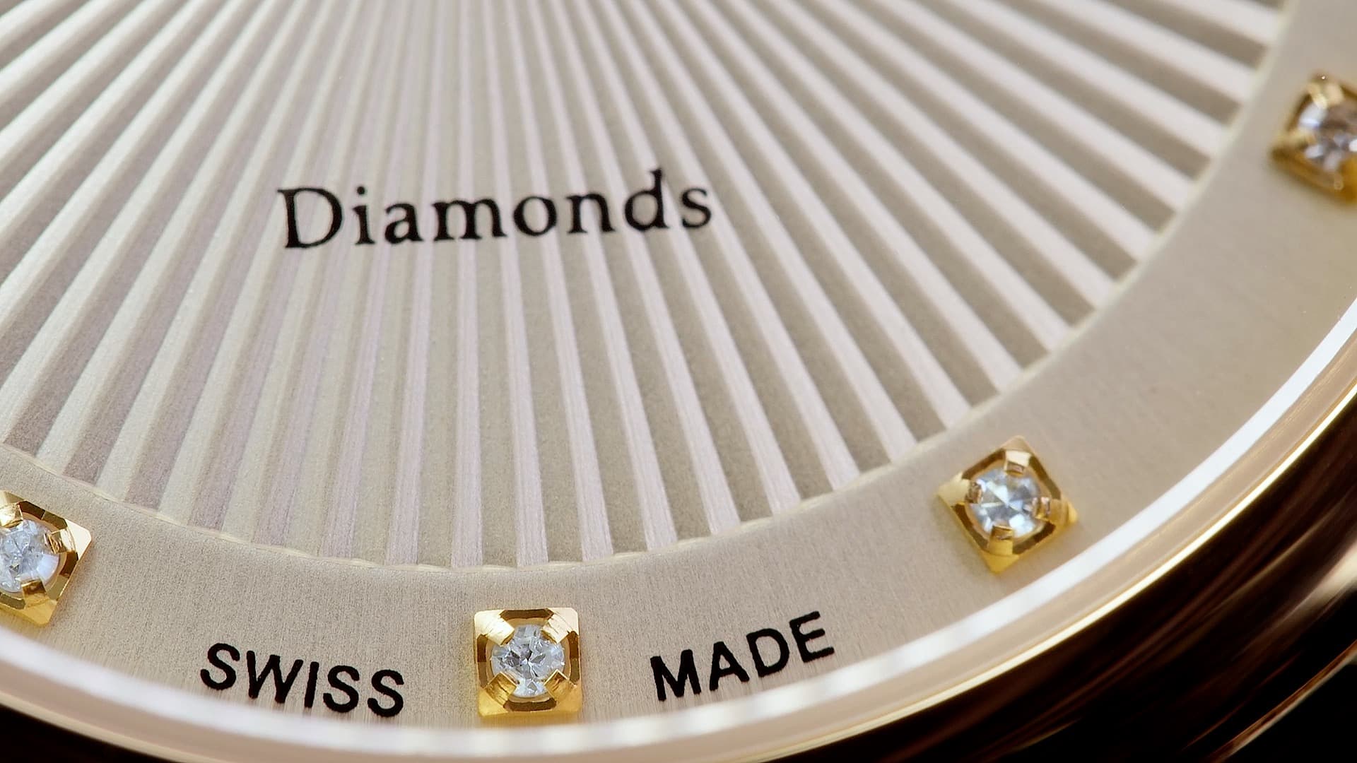 Macro detail of a Swiss Made watch dial with vertical textured finish, gold diamond-set hour markers, and “Diamonds” inscription.