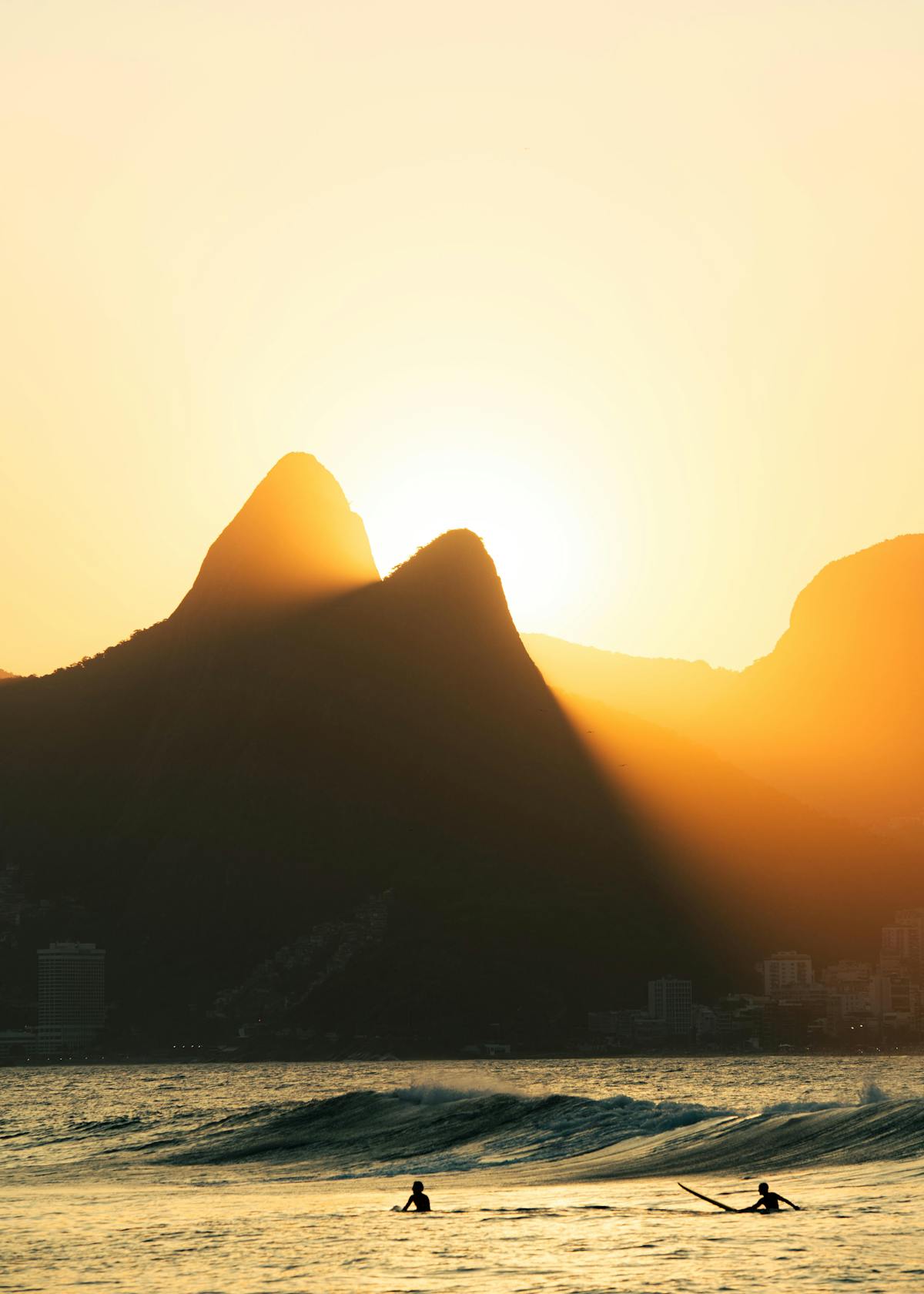 Surfers walking into the ocean at Ipanema beach at sunrise