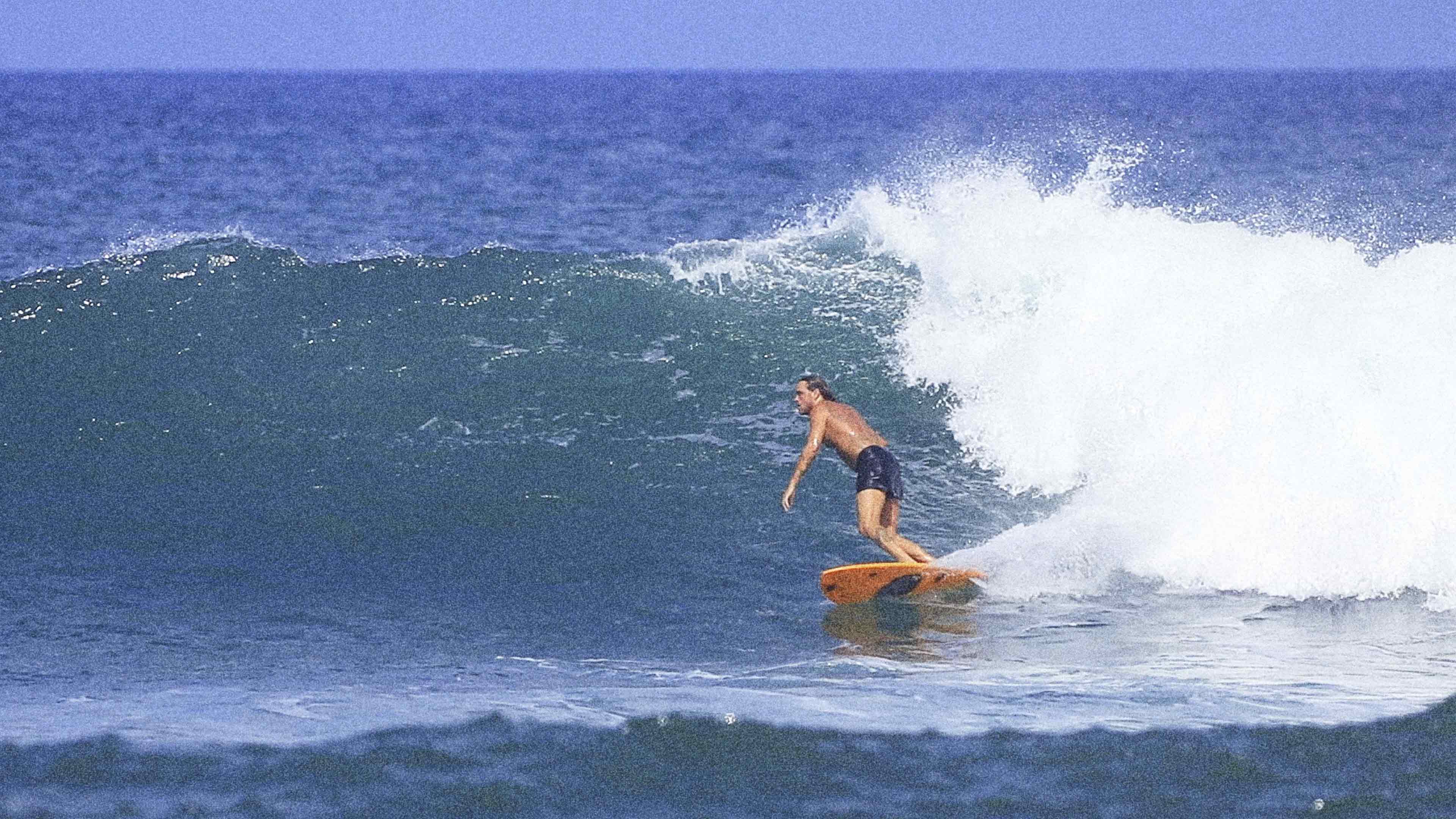 Man surfing a wave on an orange surfboard