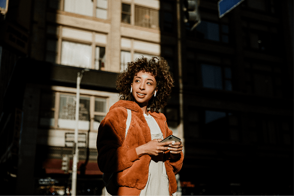 A man standing on the side of a street while talking on a cell phone