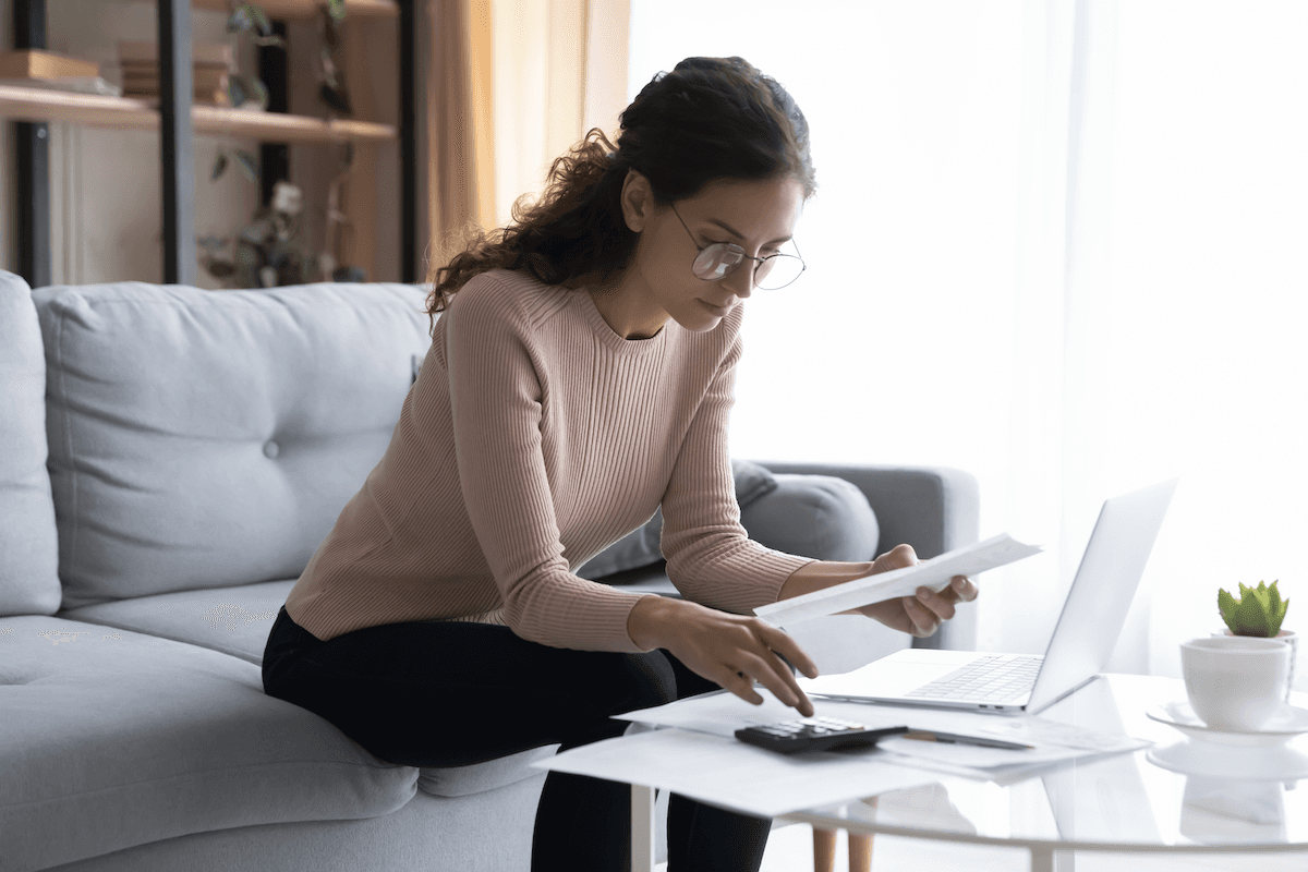 SaaS metrics: Bespectacled woman calculating bills in her living room