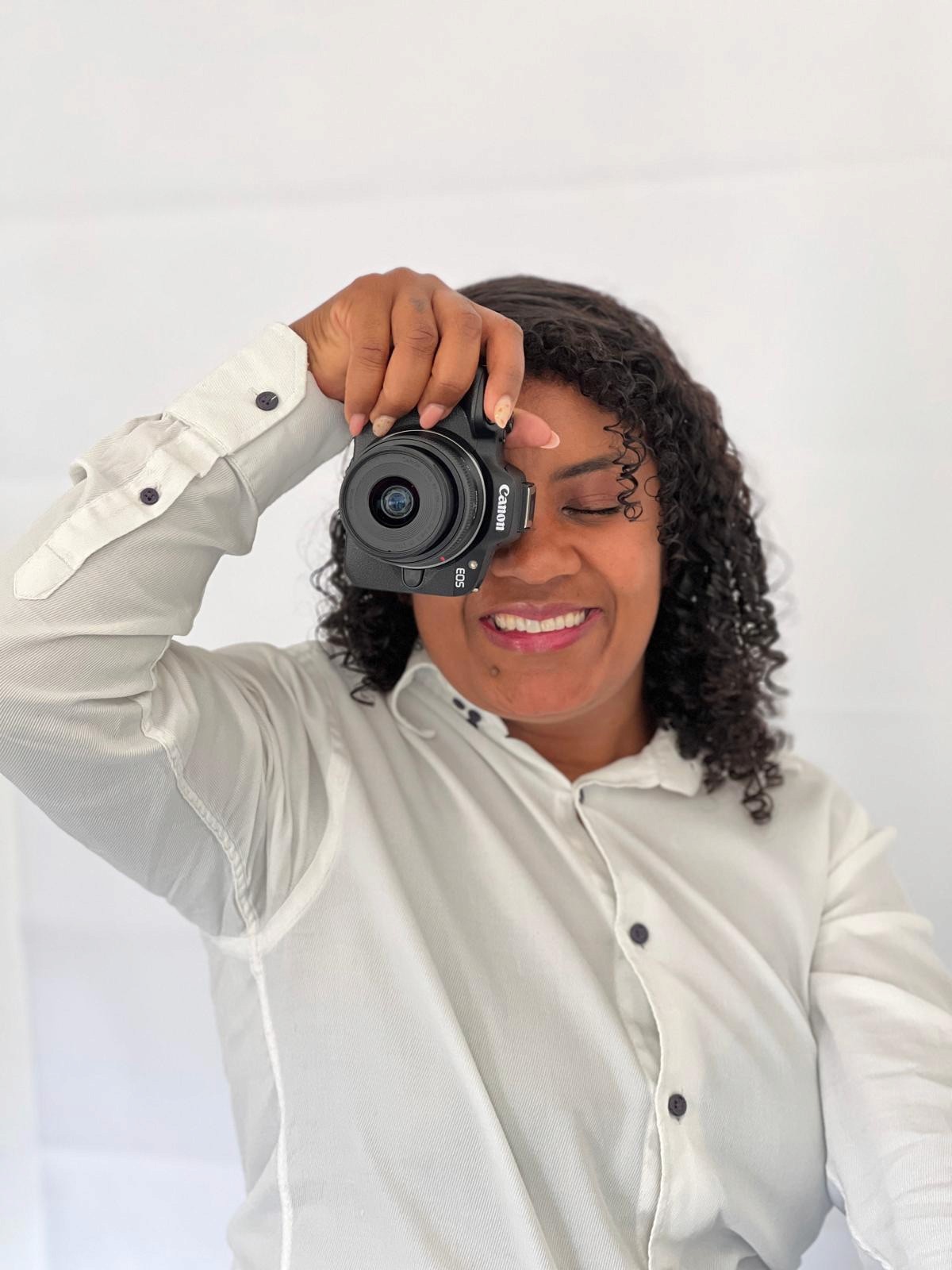 A person with short blonde hair holds a vintage camera.