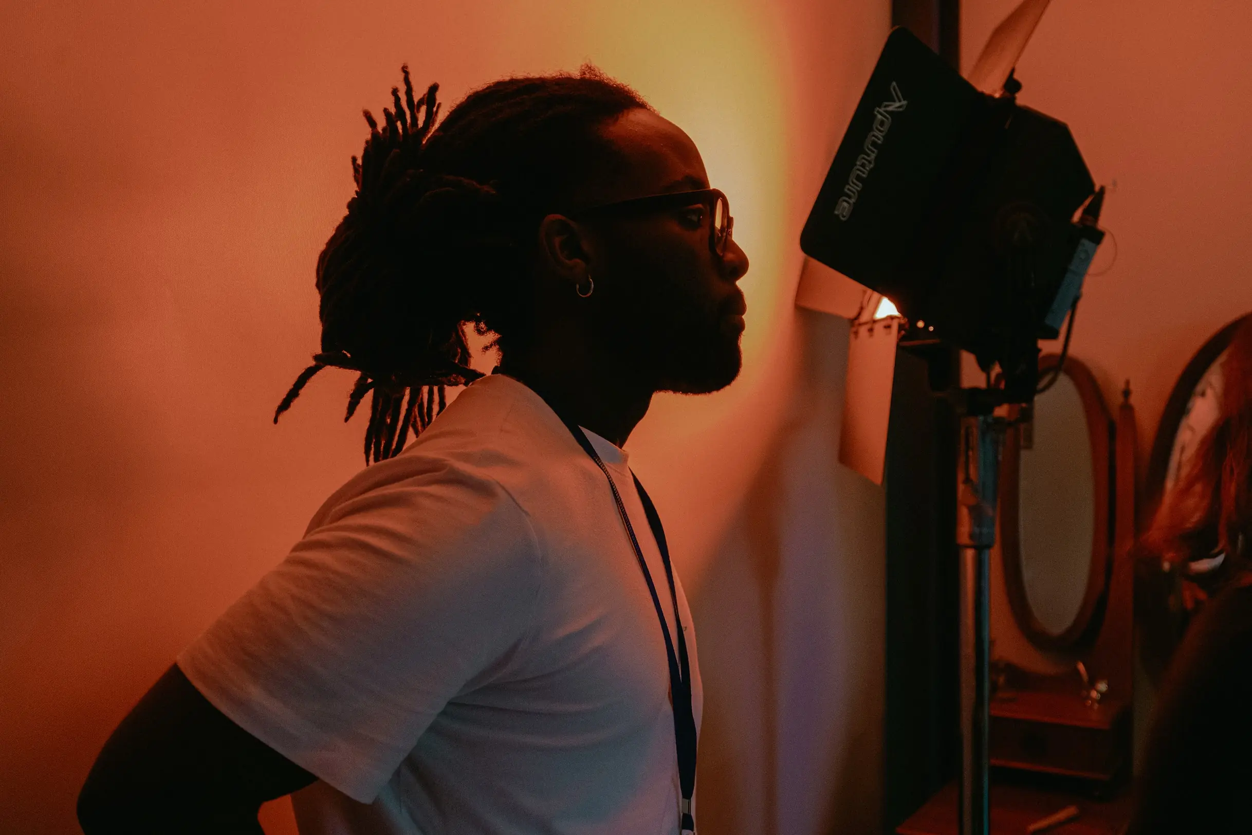 A man watching on behind the scenes of an X Anima shoot, with stage lighting in the background