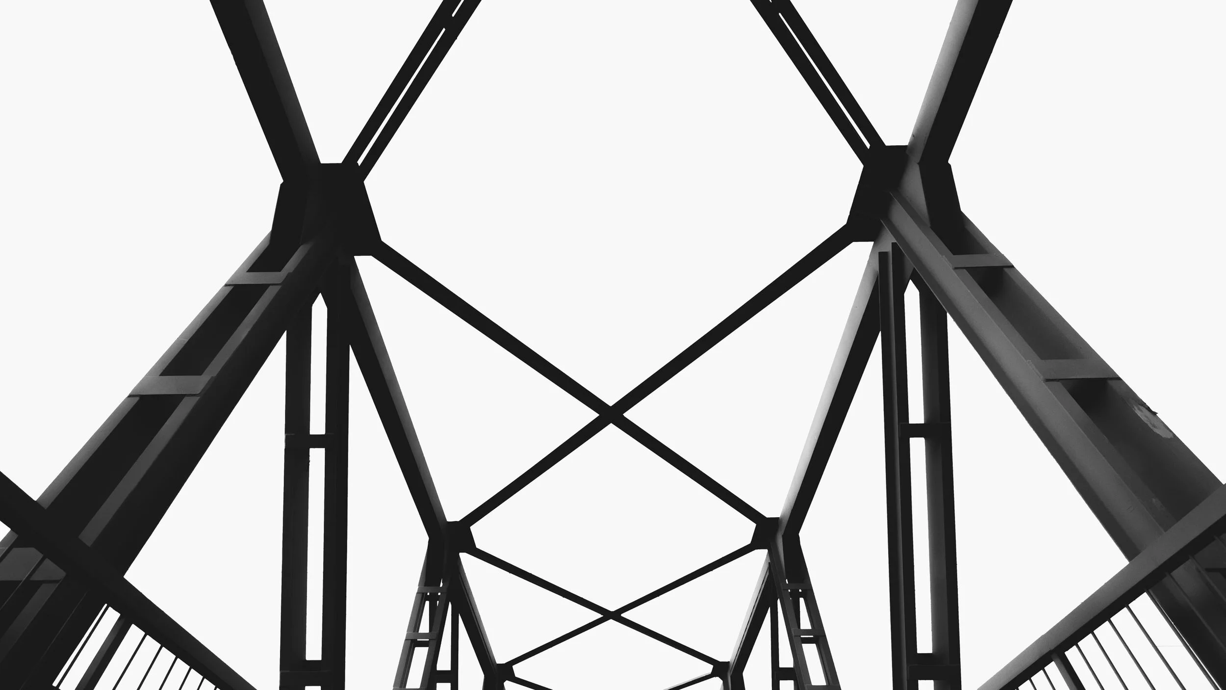 Black and white image showing an abstract view of a bridge's structural beams intersecting over highway