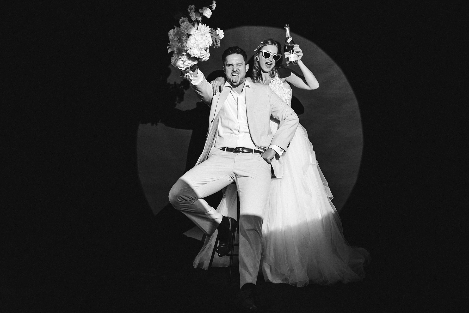 Brautpaar mit Blumenstrauß und Champagnerflasche bei einem After-Wedding-Shooting im Fotostudio, in Schwarz-Weiß.