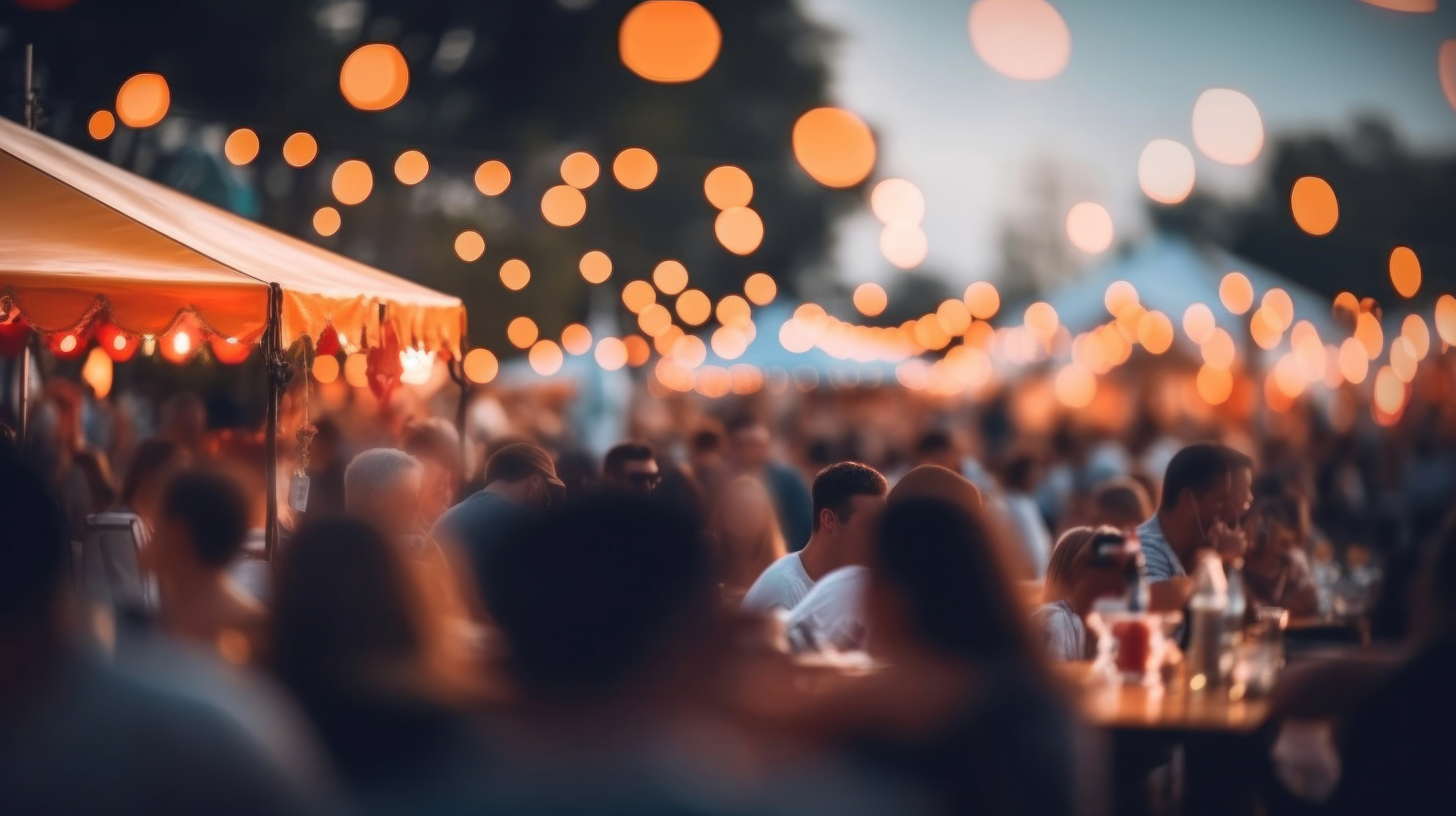 Foule attablée sous des tentes de festival illuminées de guirlandes, ambiance conviviale en soirée d’été.