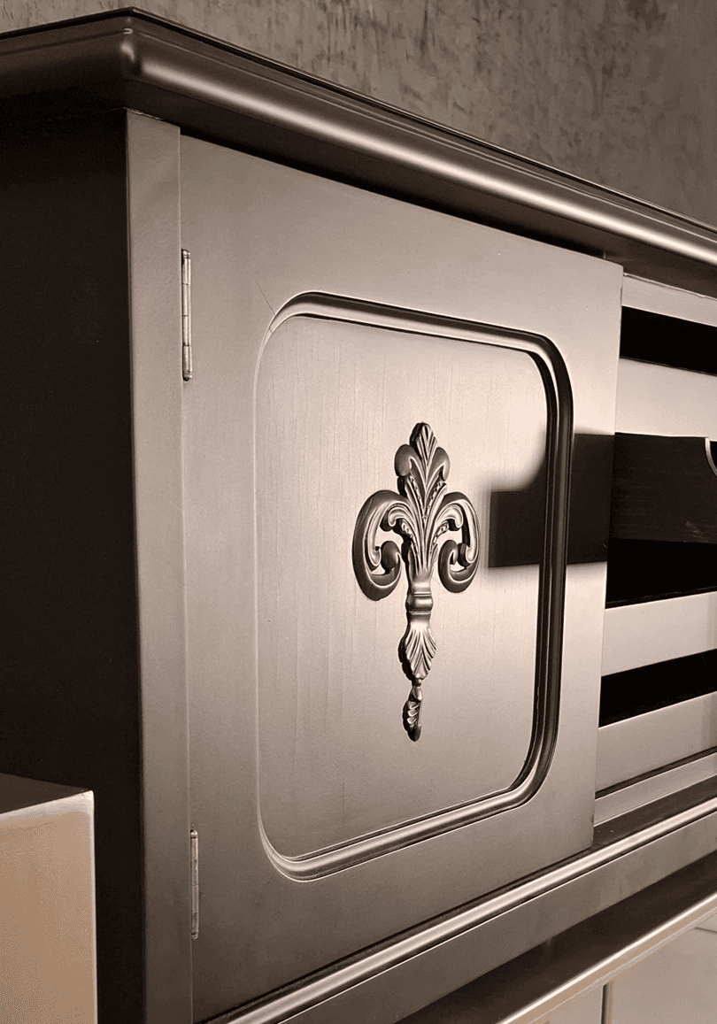 close up of fleur-de-lis ornament on the cabinet door, matte charcoal finish with refined detailing   