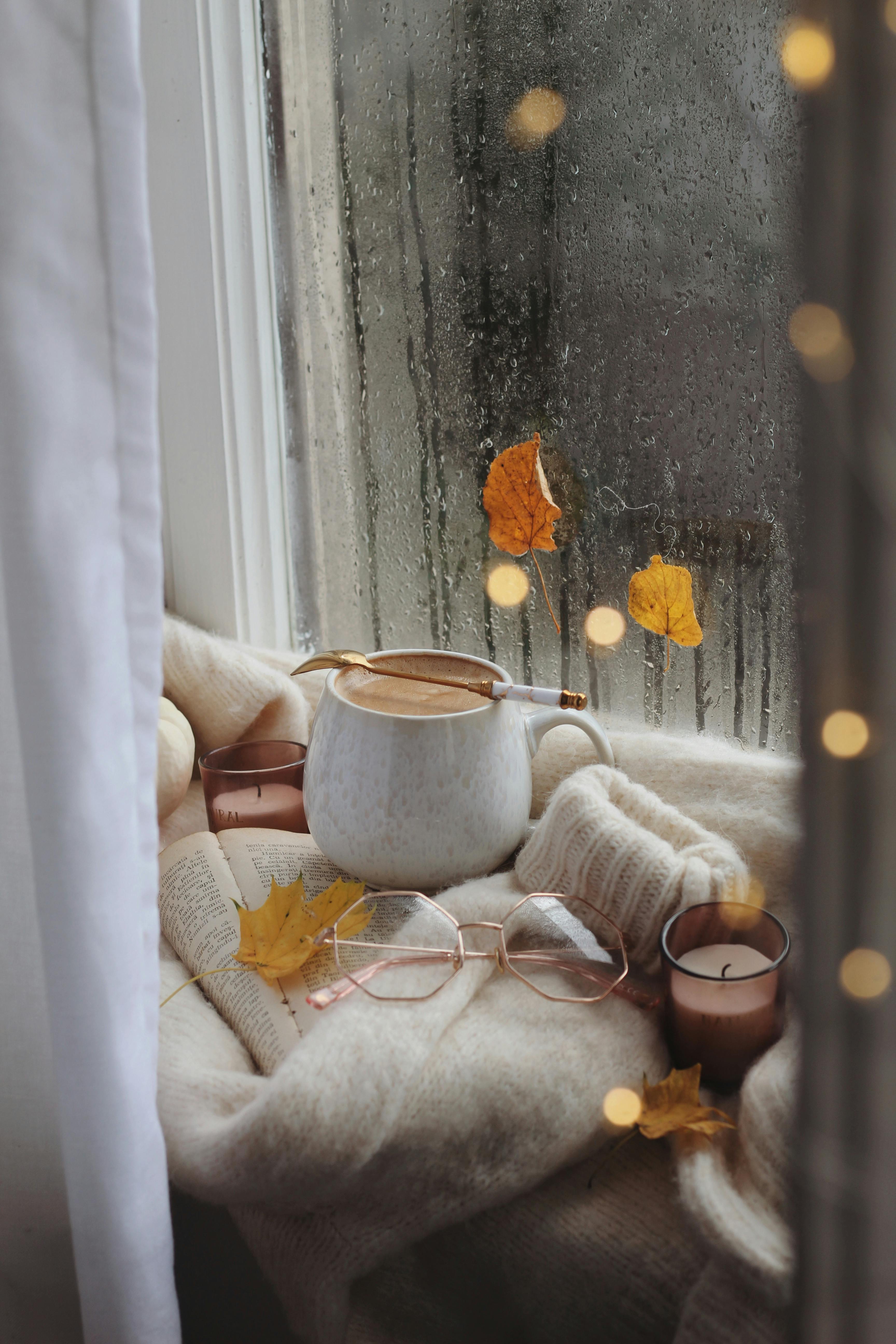 A white mug and glasses are lying on a sweater.