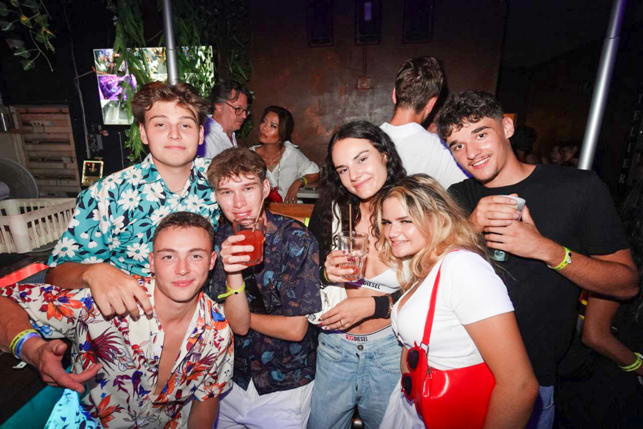 Young travelers enjoying nightlife in Nice, walking between busy bars and clubs in the city center at night.