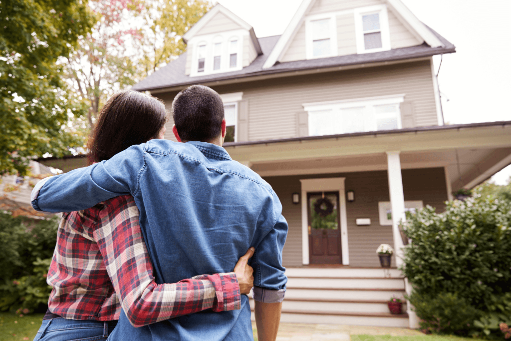 couple standing and hugging together looking happy in front of their new house to start new life