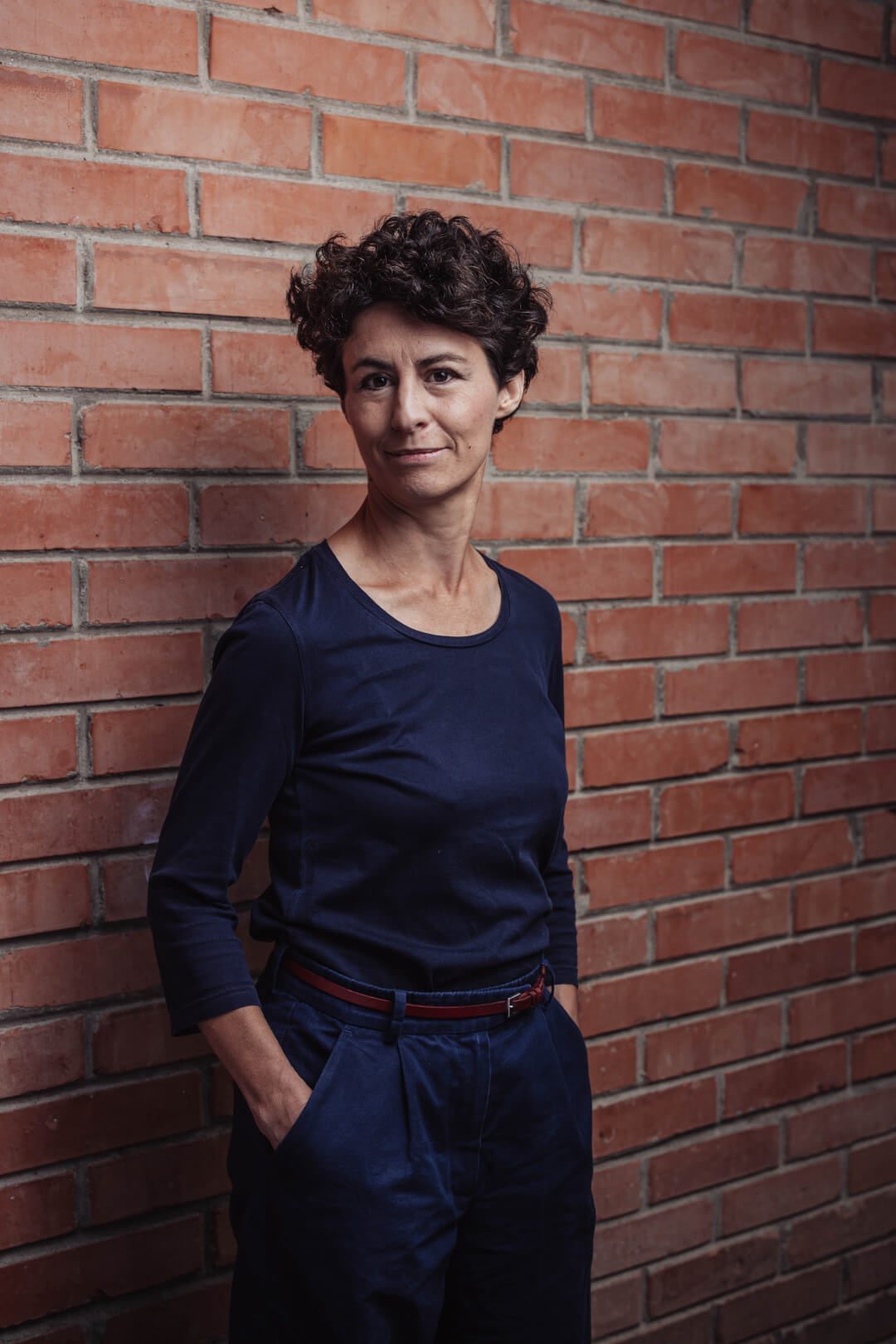 Professionelle Gastronomie- & Interieur-Fotografie: Gemütliche Lounge-Ecke mit rotem Sessel und beleuchteter Wein-Präsentation, inszeniert mit warmem Ambient-Licht und Fokus auf Design-Details.