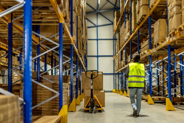 image of a man wearing high vis walking throgh a warehouse with racking of pallets either side of him