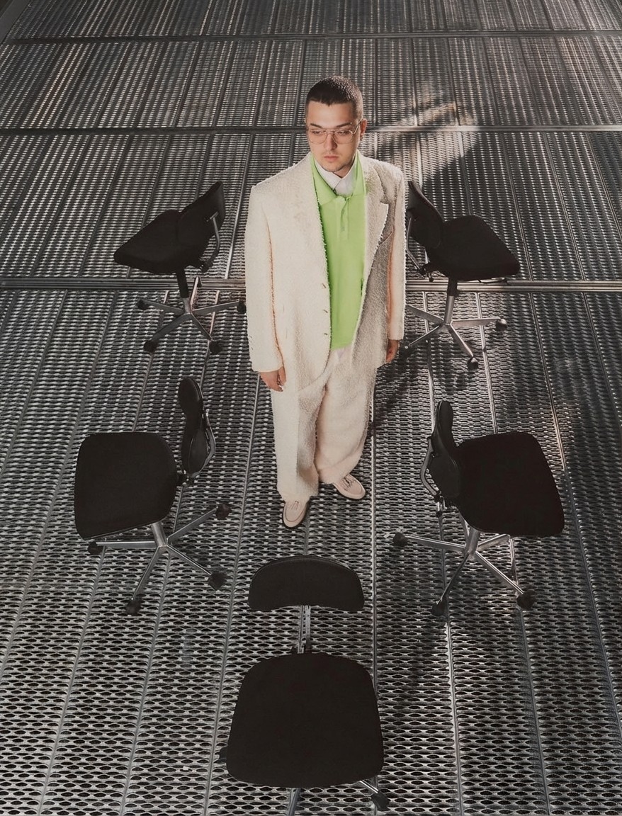 Close-up portrait of a freckled woman with soft pink hair and star earring, natural light, white tank top.