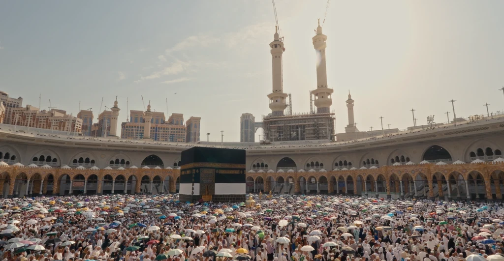 Crowds surrounding Kaaba, sunlight sollhouetting the two towers on the edge.