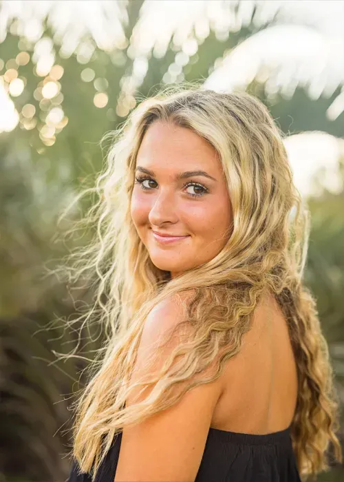 Senior girl with long wavy blonde hair looking back over her shoulder