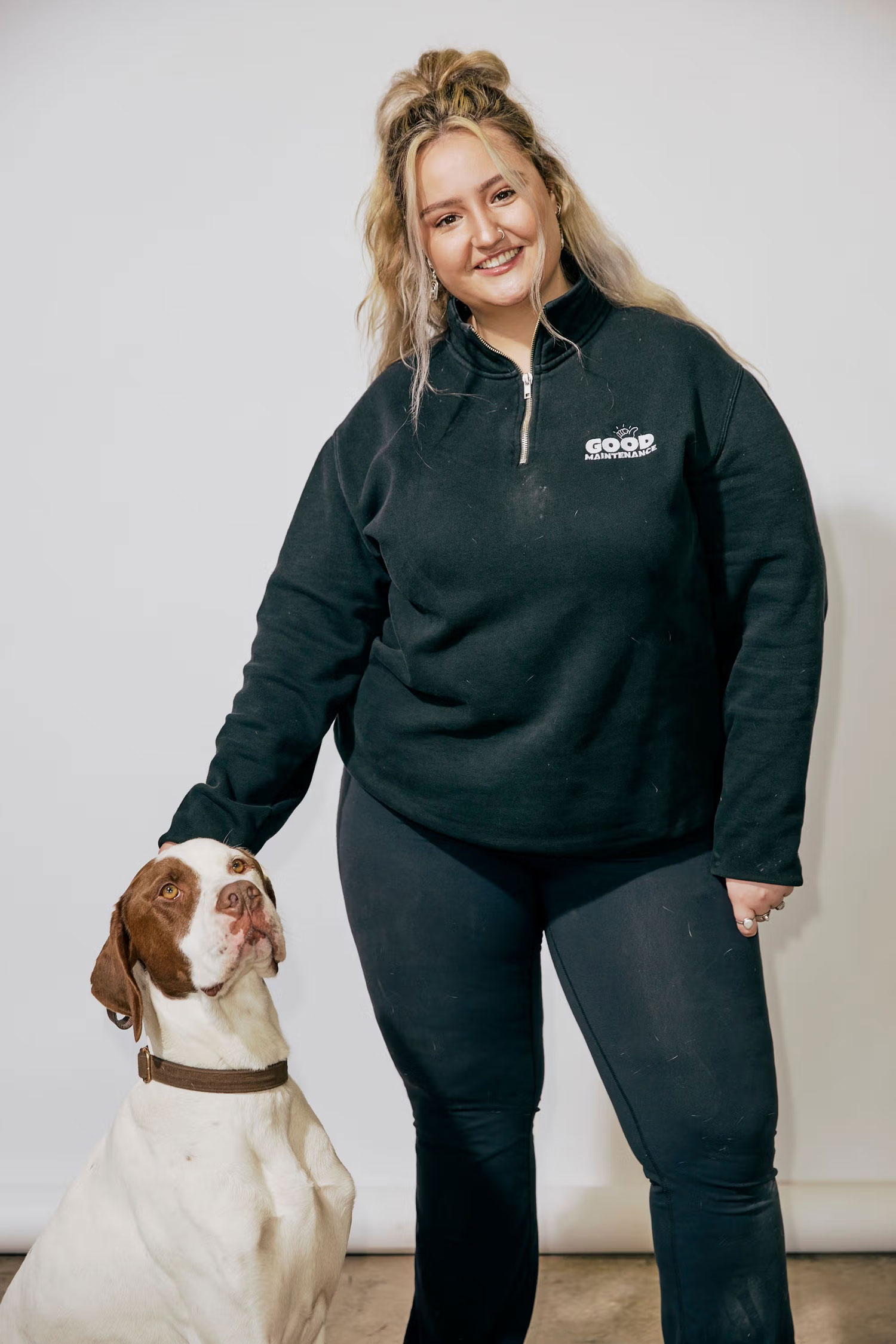 Good Maintenance team member posing with company dog against a studio background.