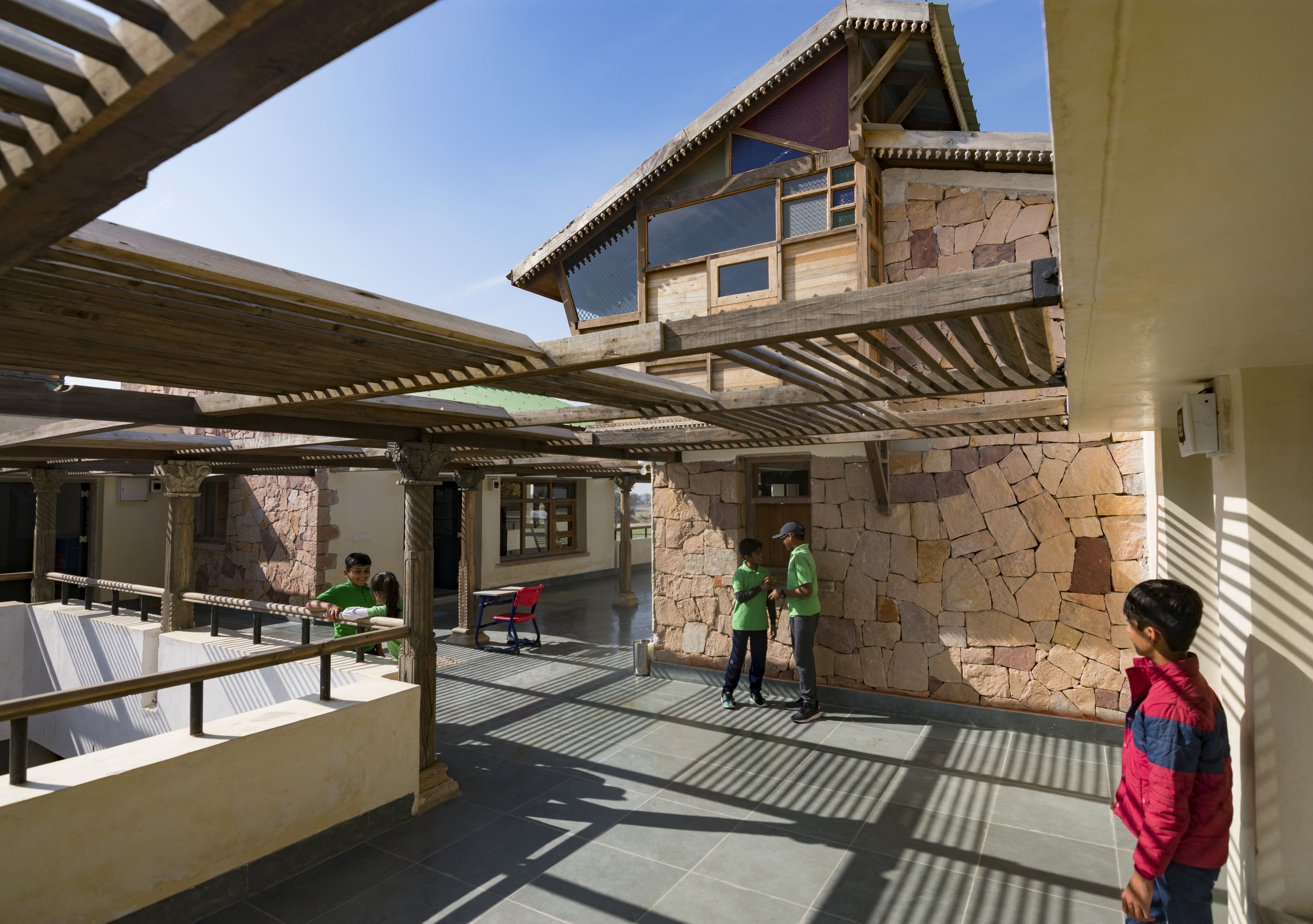 A teacher stands near a whiteboard in a classroom, explaining a lesson to the students.