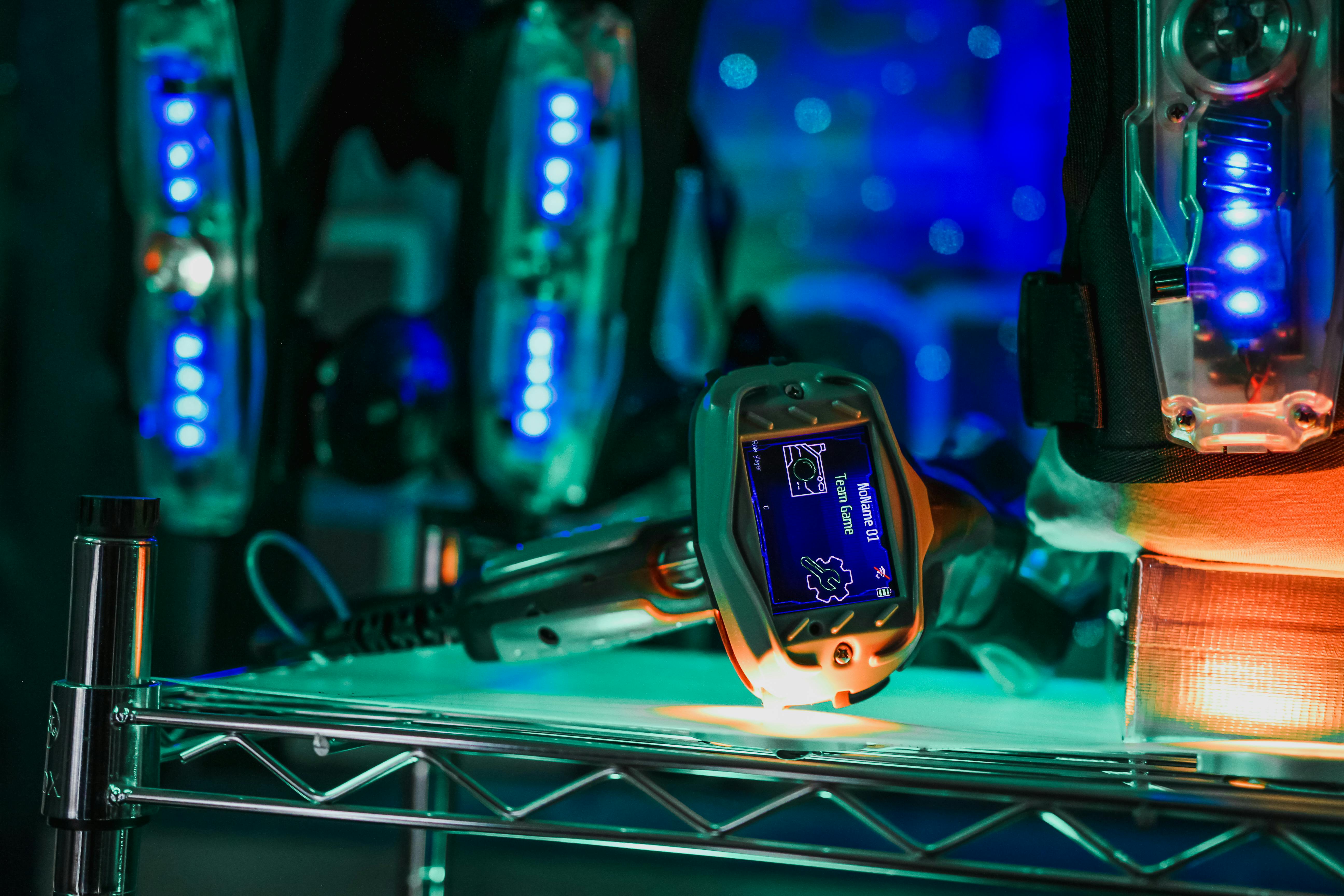 A young person with curly hair smiles at the camera while sitting in front of a laptop against a dark background.