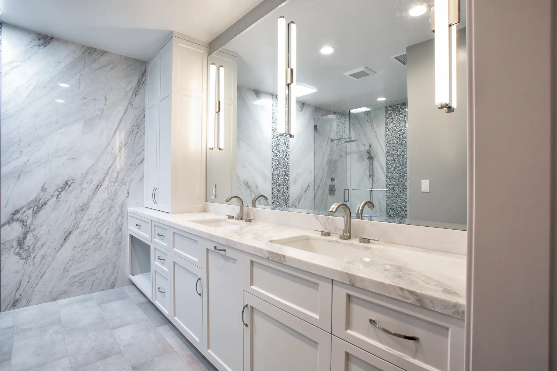 Spacious bathroom with dual vanity, white cabinetry, large mirrors, and tile flooring in Costa Mesa Remodel. Photo by Chris Darnall.