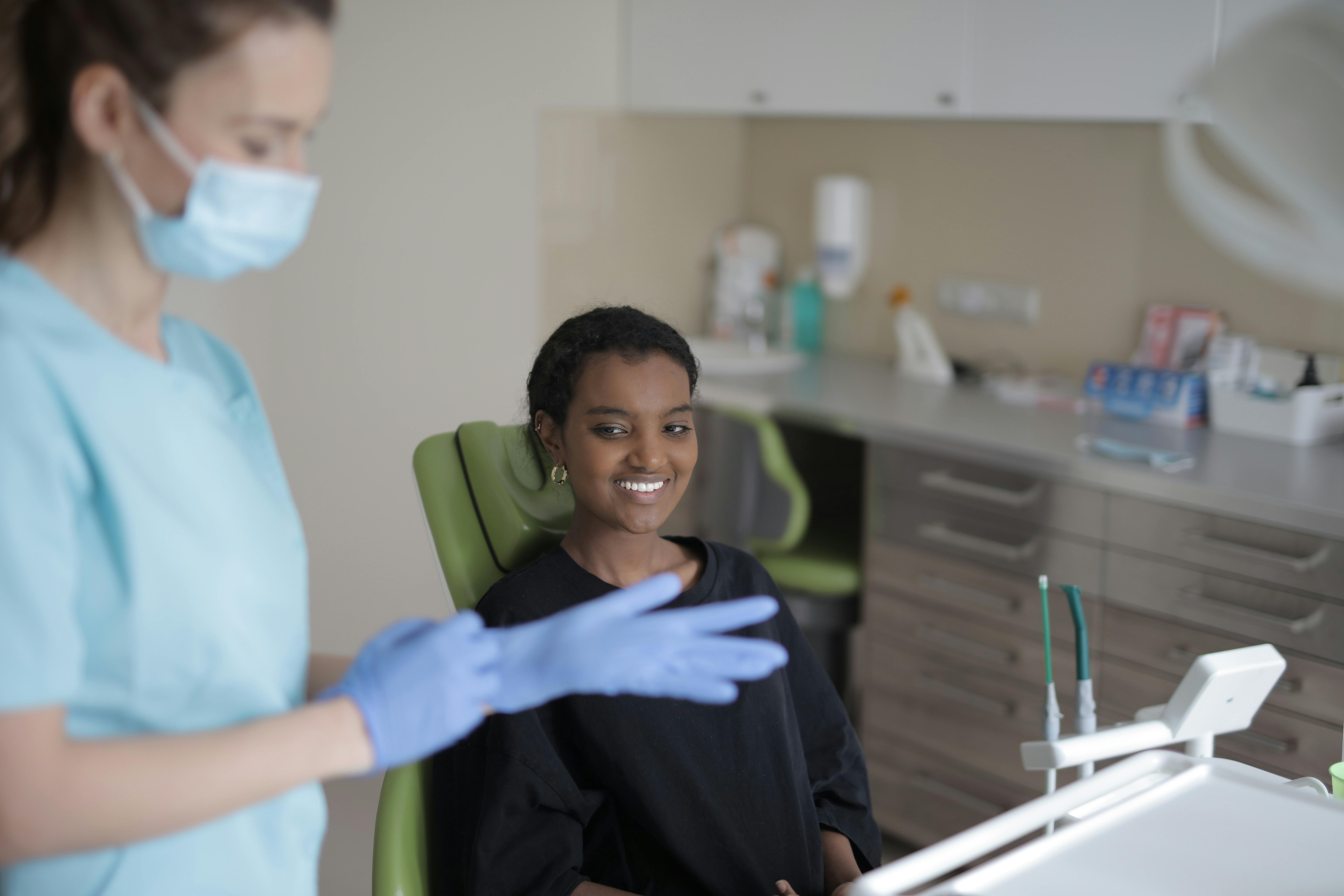 dental hygienist putting on sterile gloves while patient smiles in chair