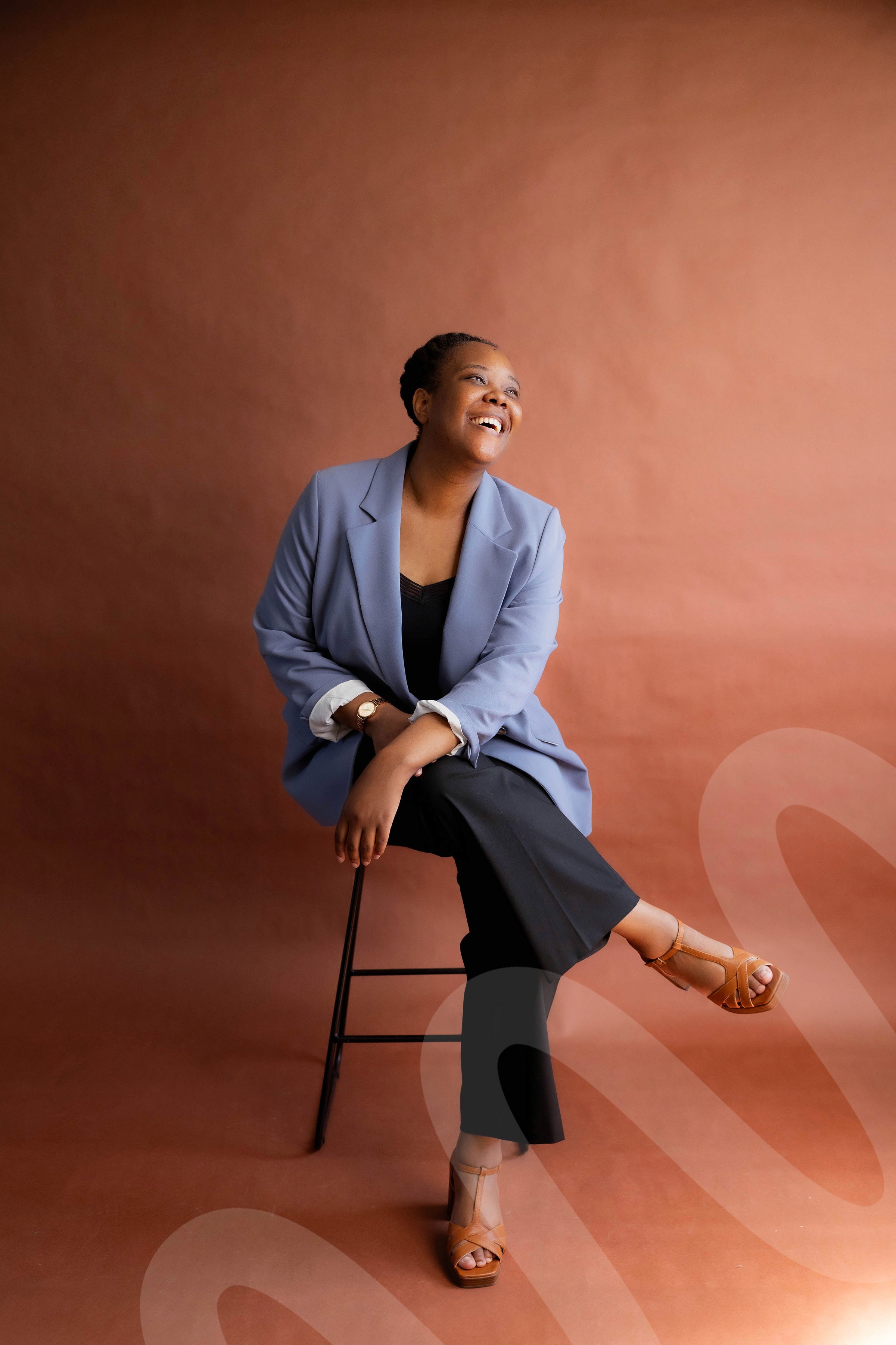 Image shows the founder Ranica sat on high stool smiling.
