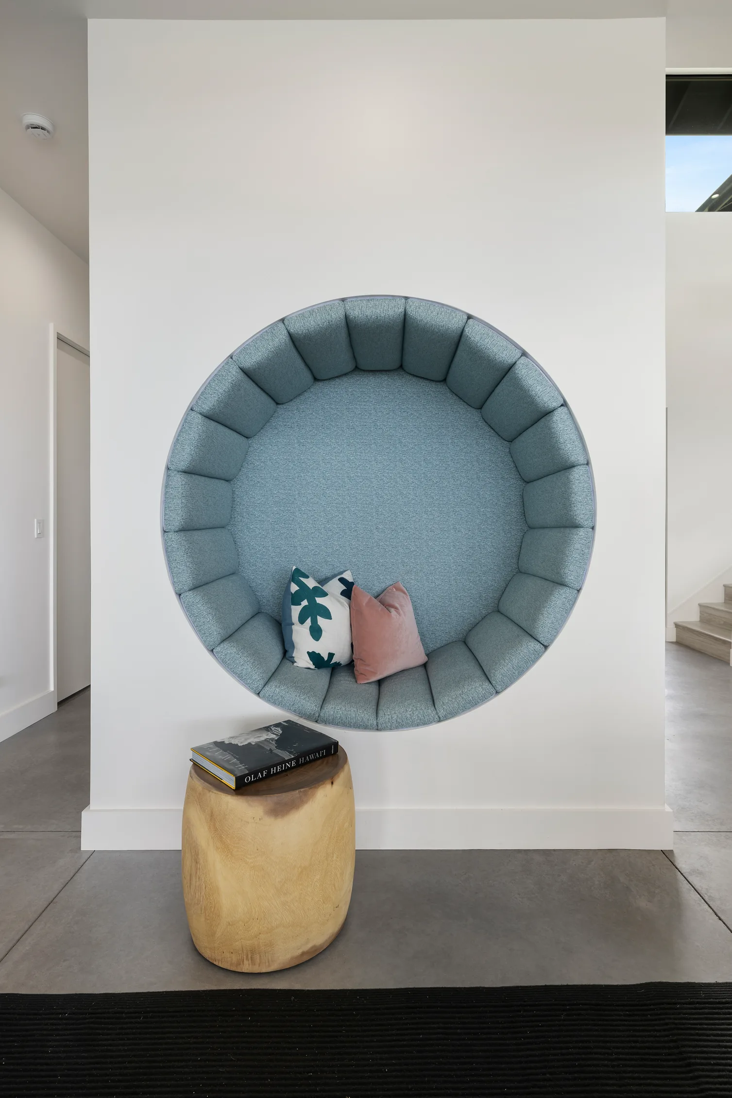 blue circular sitting space inlaid into white wall, reading nook.