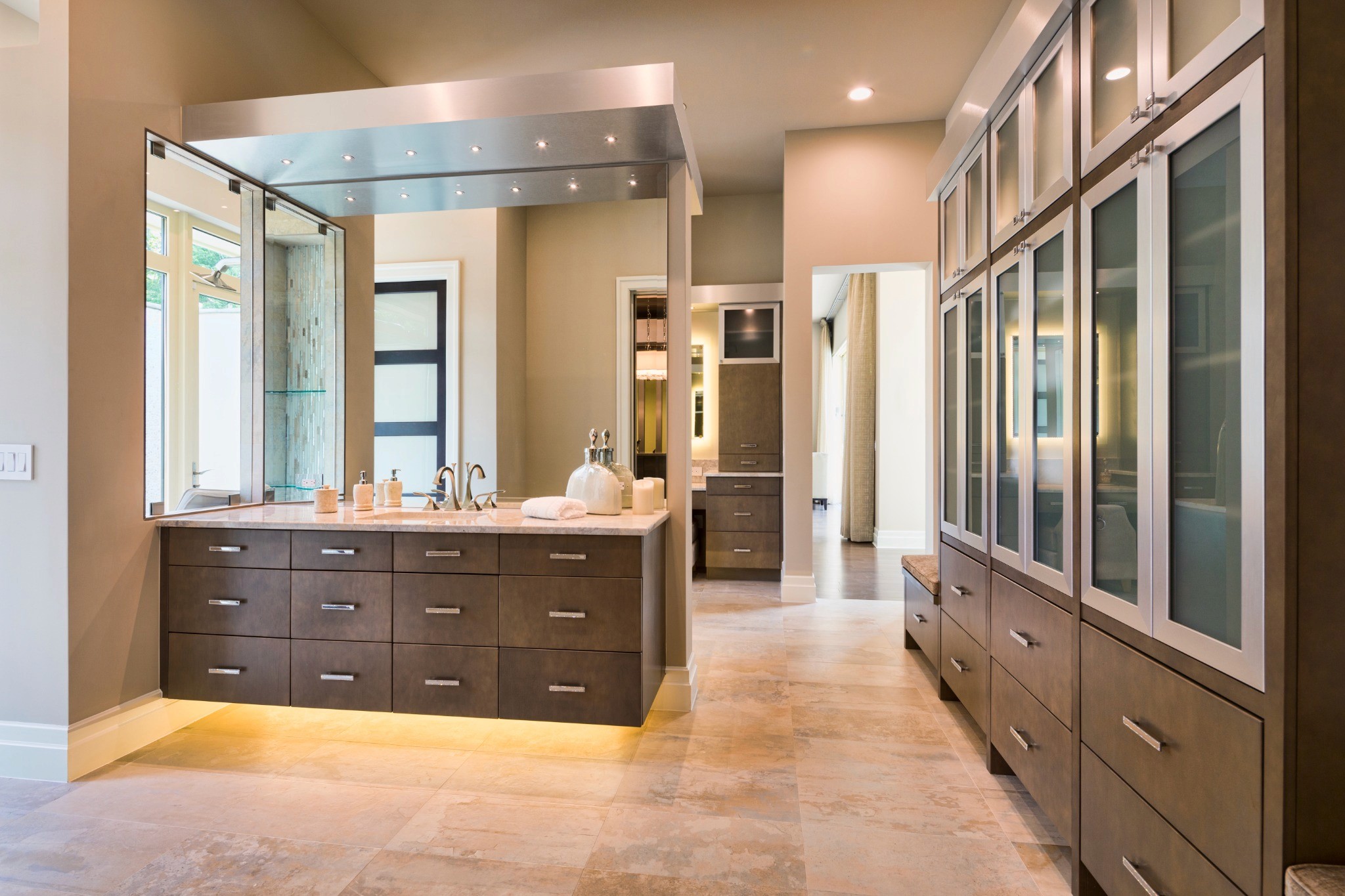 Luxurious bathroom renovation featuring floating vanity with under-cabinet lighting, sleek bronze-toned cabinetry, dual sinks, and frosted glass storage units, reflecting B&Y Reno Corp’s attention to detail and modern design in home remodels.