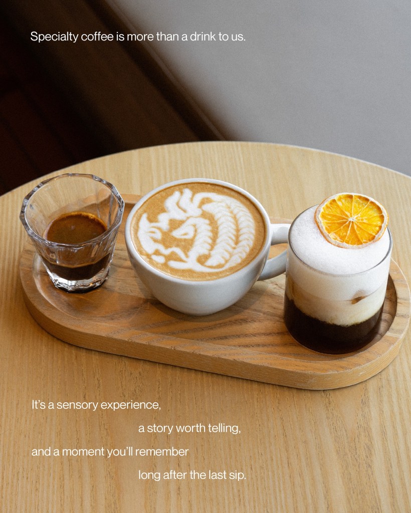 A beautifully arranged coffee flight on a wooden tray featuring a latte with intricate art, a shot of espresso, and a creative coffee drink topped with a slice of orange, accompanied by a quote about the sensory experience of specialty coffee.