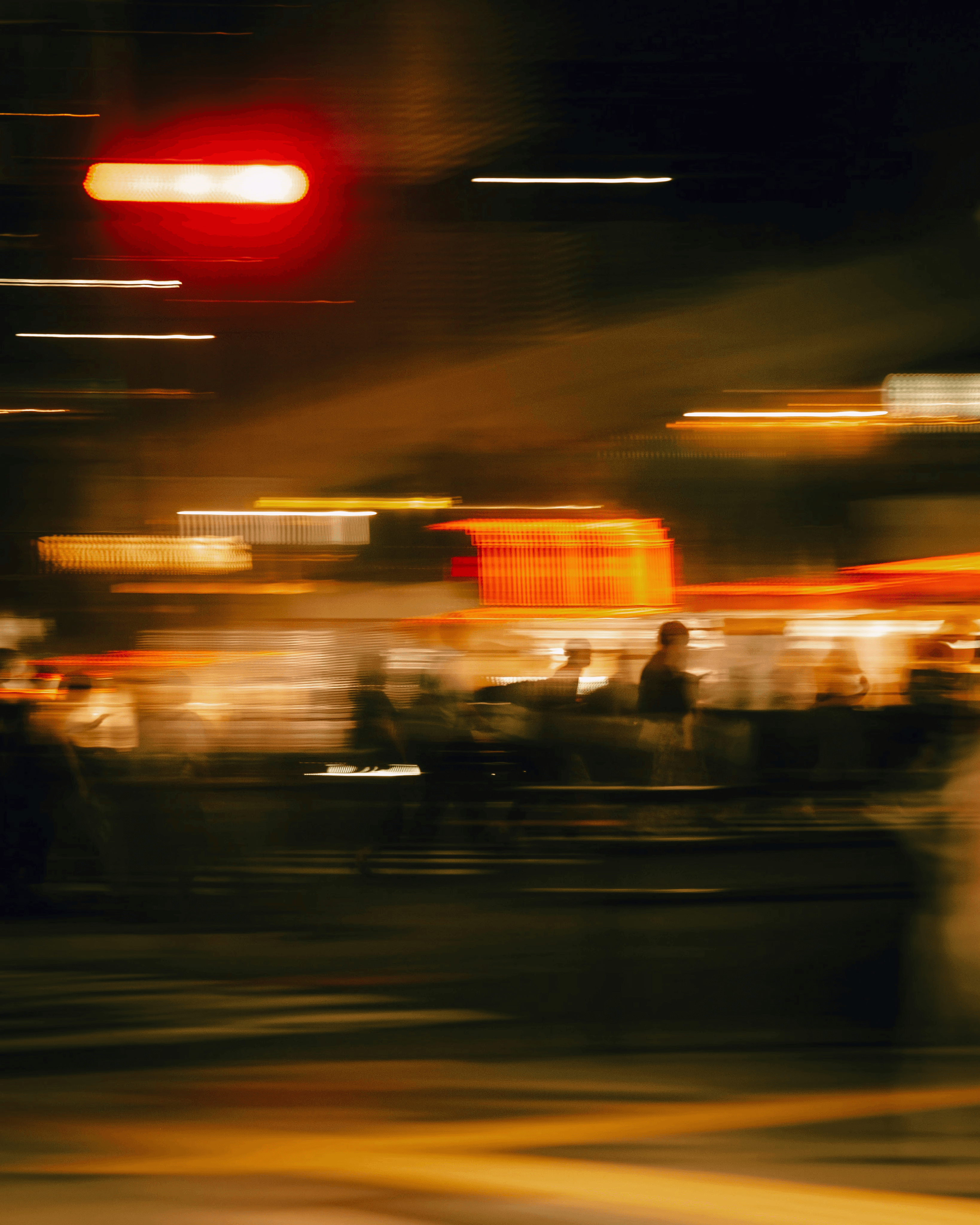 Blurry cityscape with red light and street lights at night.