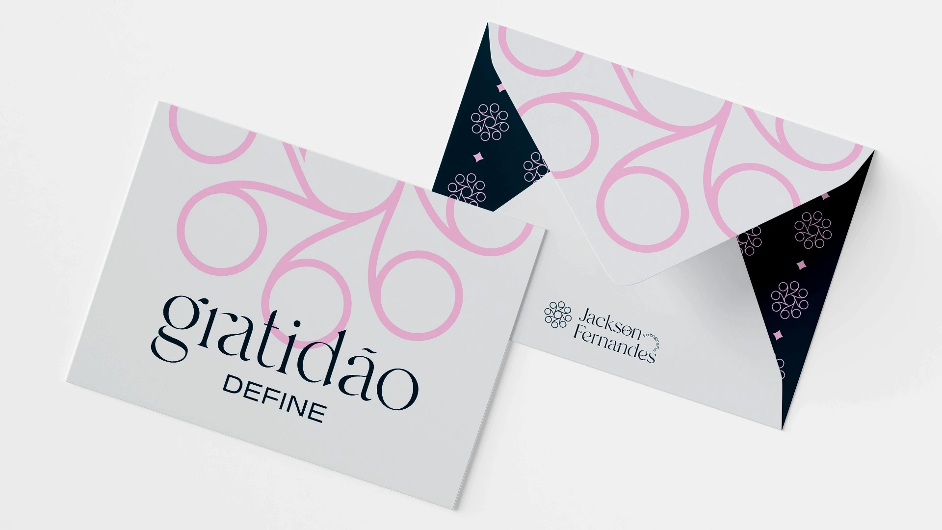 Envelope corporativo e cartão com a palavra 'gratidão DEFINE' estampada em azul-escuro, apresentando grafismos abstratos na cor rosa e o logotipo Jackson Fernandes Fotografia.
