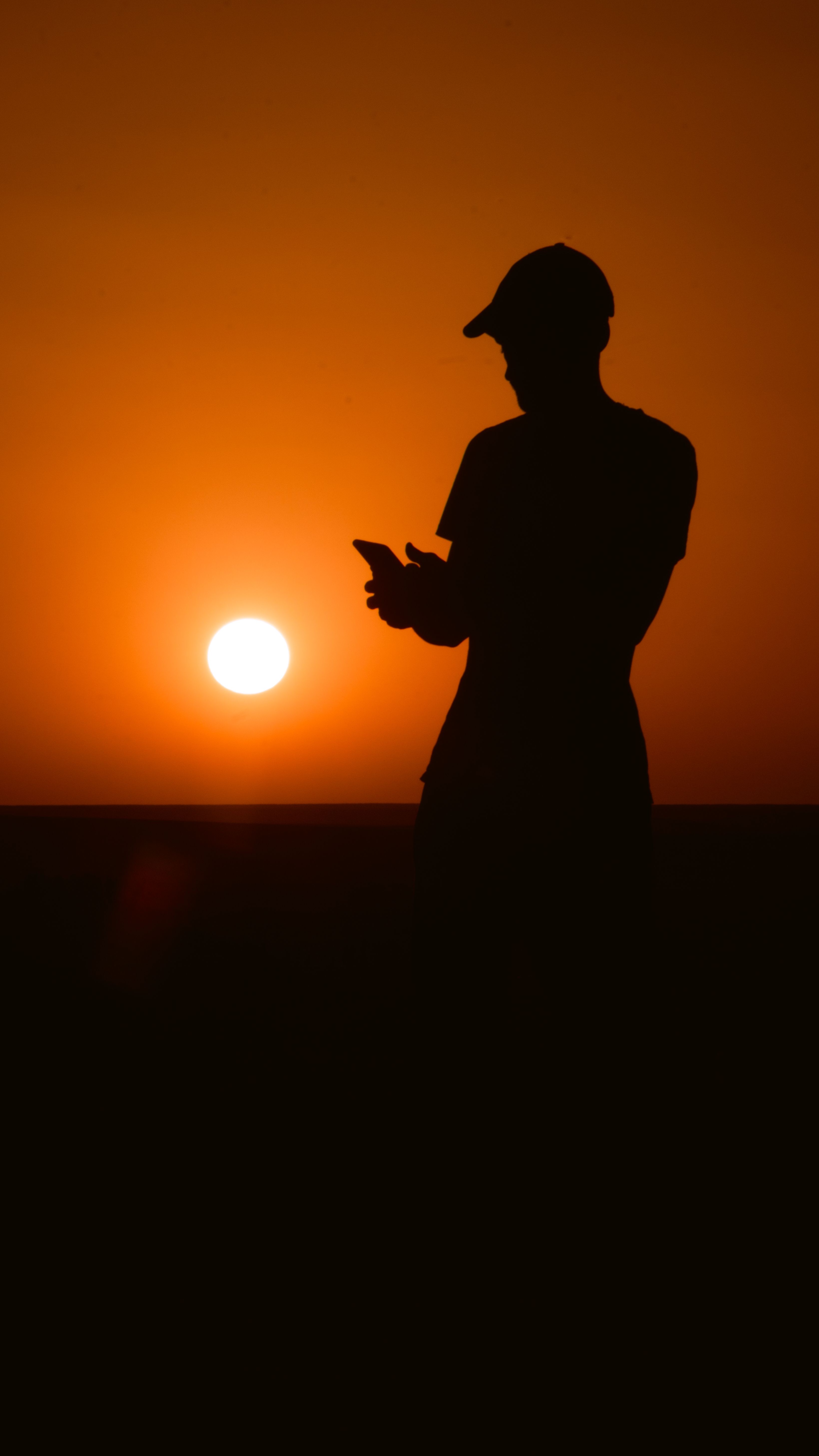 Silhouette of a person against a vibrant sunset in Aoulef, Algeria.