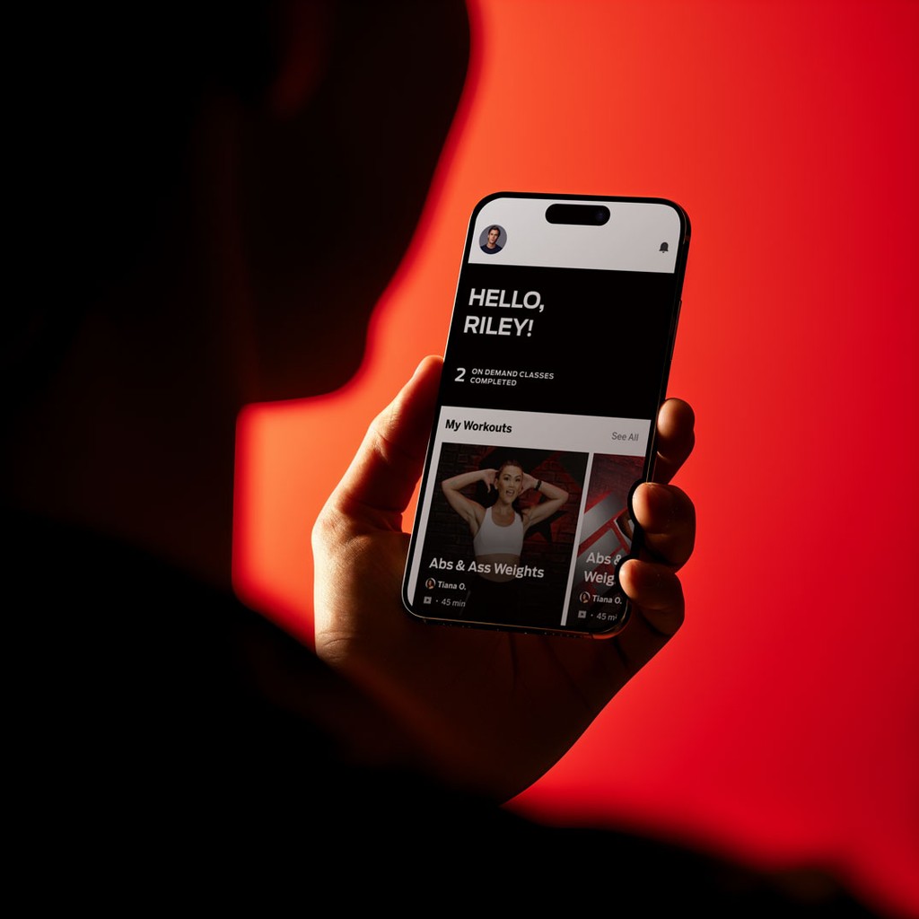 Person holding a smartphone displaying a modern fitness app interface, representing STRV’s expertise in building scalable digital products for tech innovators and investment partners.