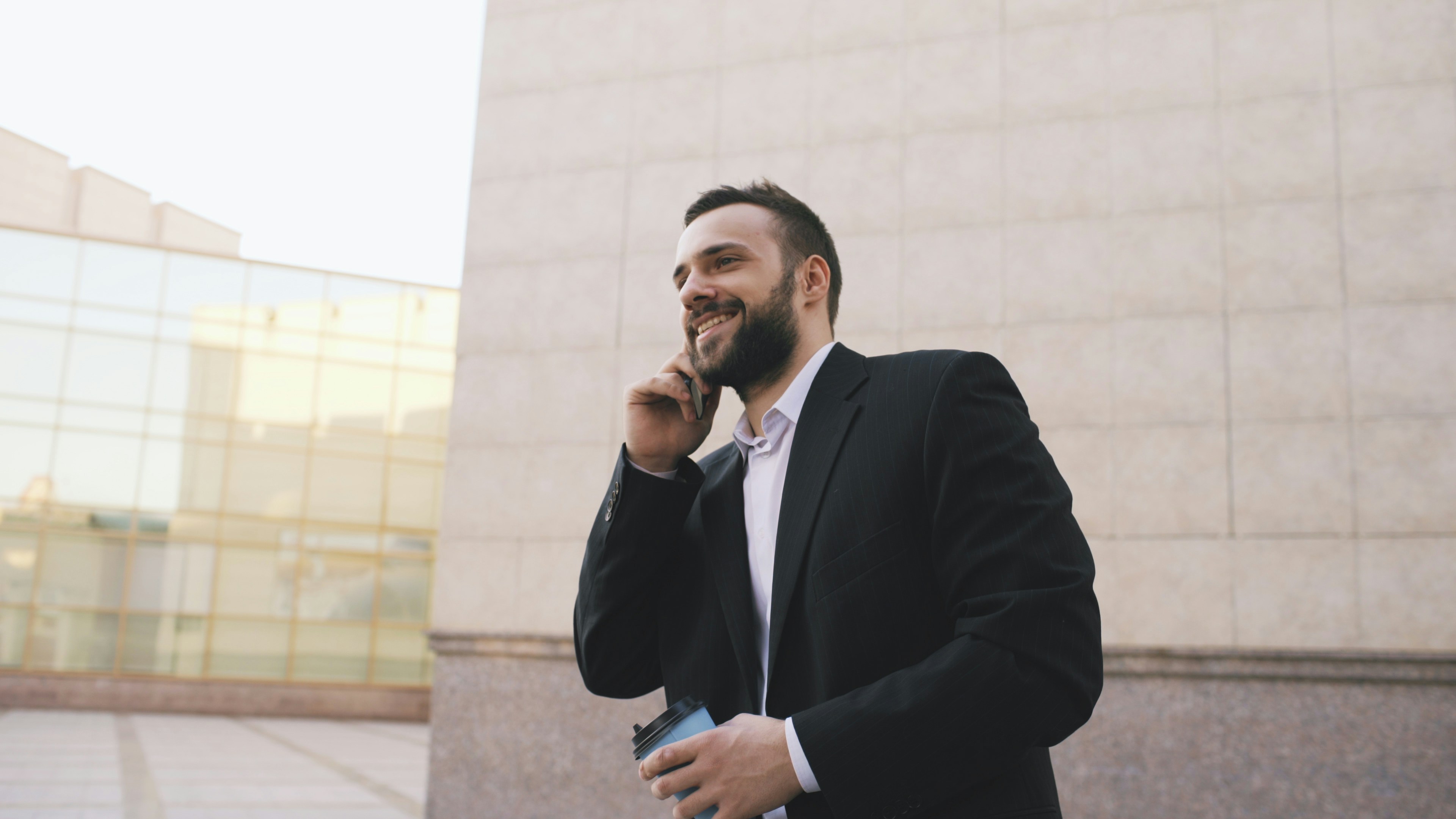Man in suit talking on phone holding coffee cup